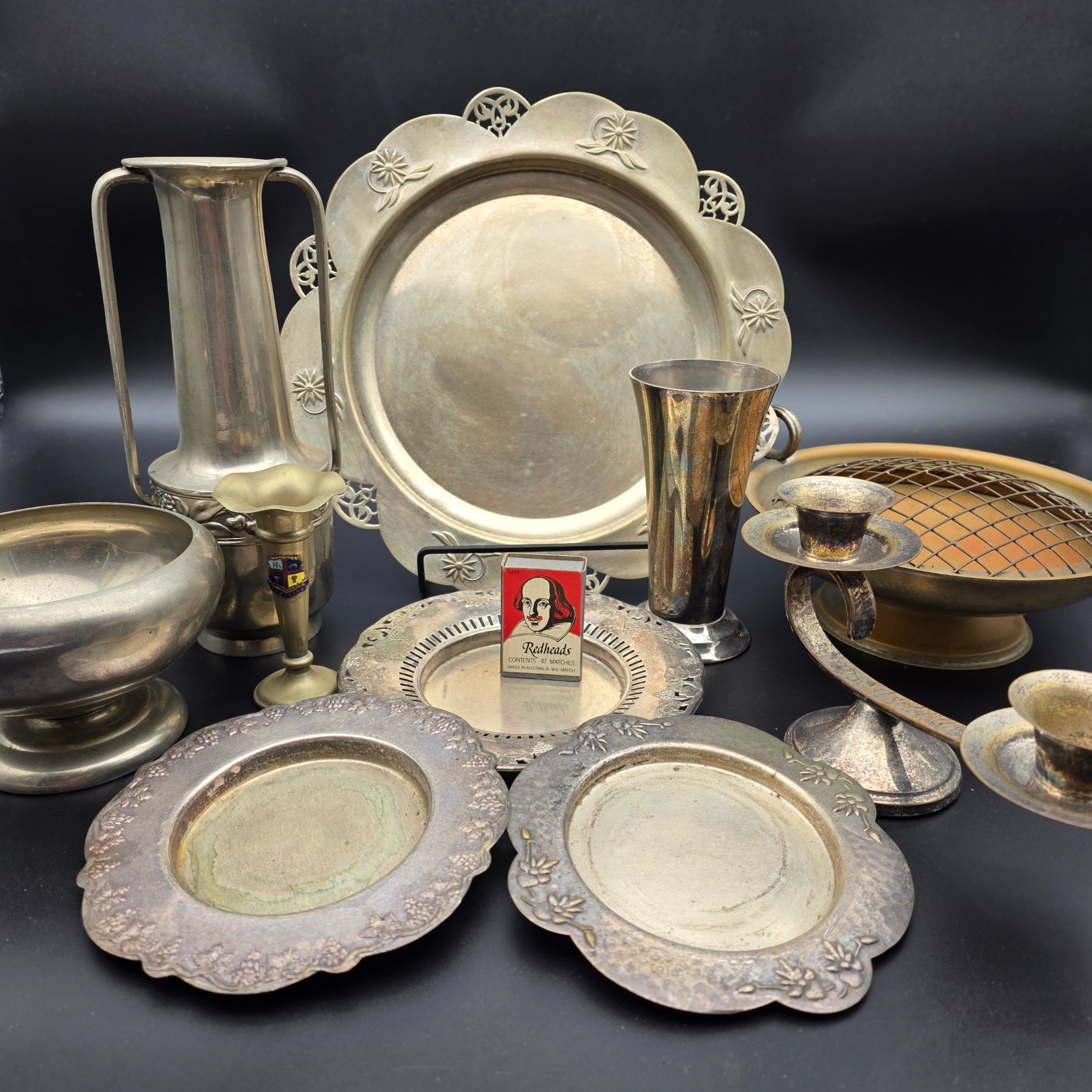 A varied collection of vintage homewares crafted from Britex Electroplated Britannia Metal (E.P.B.M.), 'Made in England', including trays, a pitcher, bowls, and a candelabra, all exhibiting significant tarnishing.