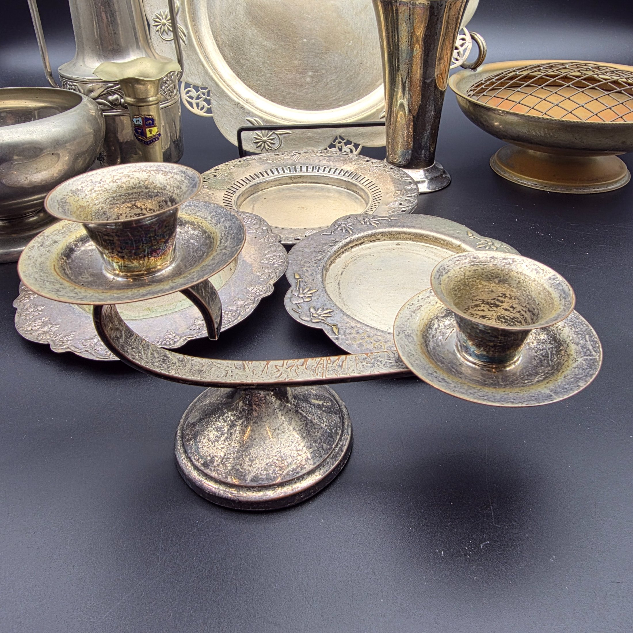 A varied collection of vintage homewares crafted from Britex Electroplated Britannia Metal (E.P.B.M.), 'Made in England', including trays, a pitcher, bowls, and a candelabra, all exhibiting significant tarnishing. - View 4