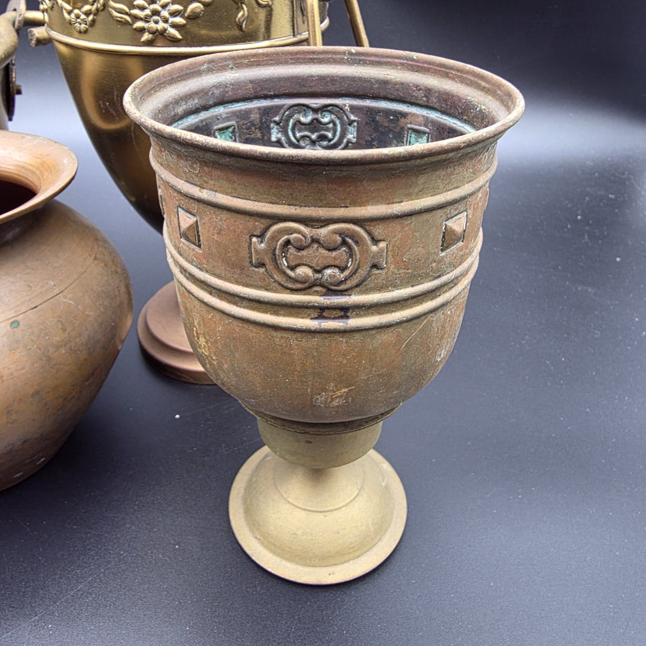 A varied collection of five vintage decorative vessels crafted from brass and copper, including a small footed goblet, a rounded copper pot, a brass bucket with a handle, a tall handled brass urn, and a footed brass goblet with ornate banding. At least one piece bears a 'MADE IN INDIA' label, indicating a probable origin for the entire group. - View 2