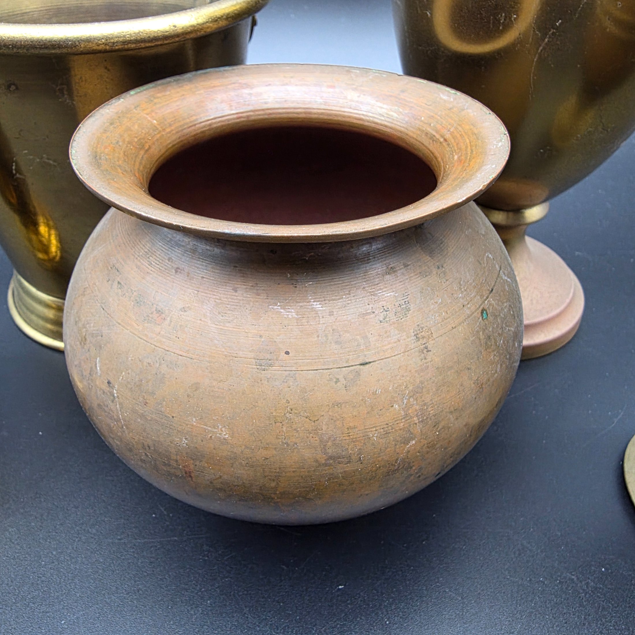 A varied collection of five vintage decorative vessels crafted from brass and copper, including a small footed goblet, a rounded copper pot, a brass bucket with a handle, a tall handled brass urn, and a footed brass goblet with ornate banding. At least one piece bears a 'MADE IN INDIA' label, indicating a probable origin for the entire group. - View 3