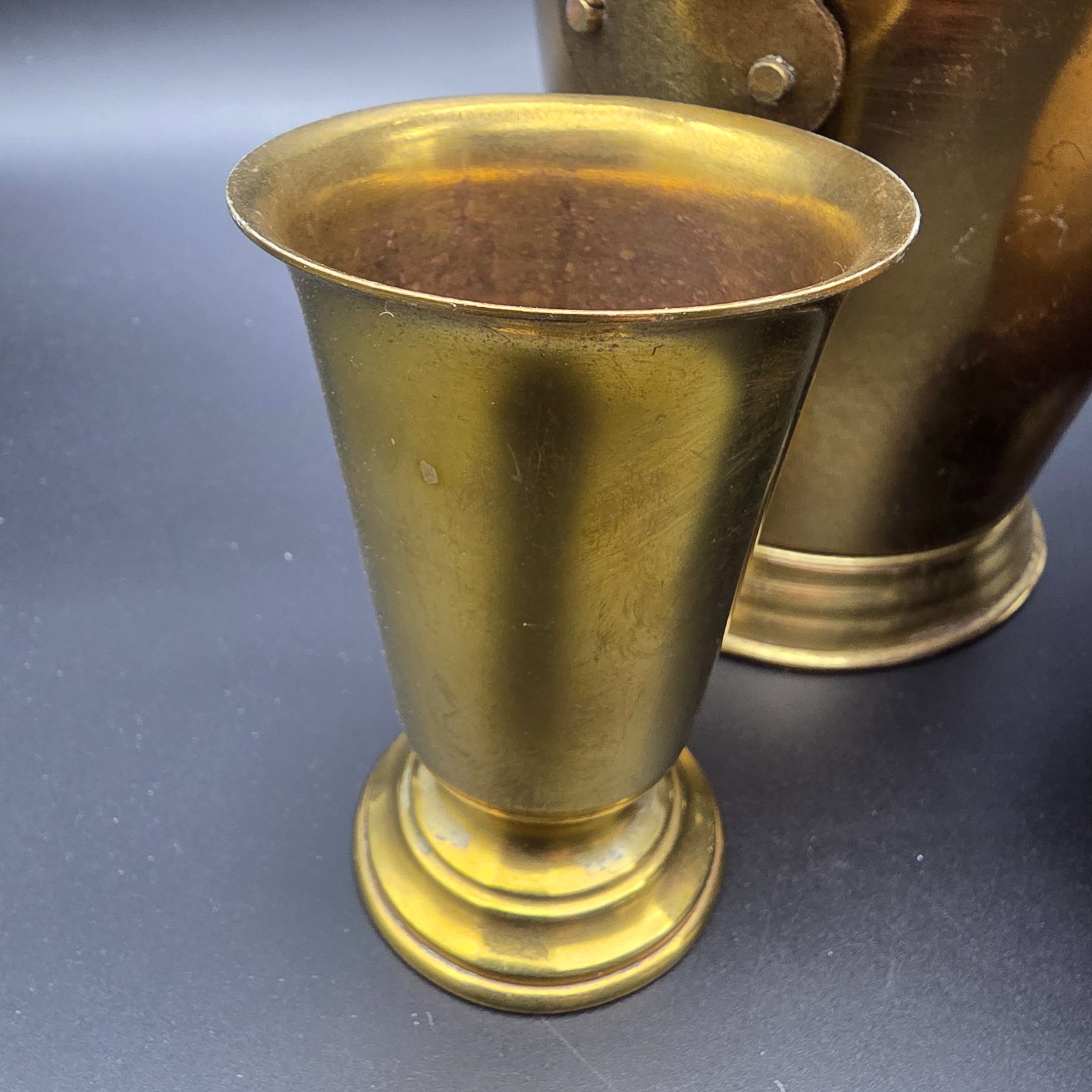 A varied collection of five vintage decorative vessels crafted from brass and copper, including a small footed goblet, a rounded copper pot, a brass bucket with a handle, a tall handled brass urn, and a footed brass goblet with ornate banding. At least one piece bears a 'MADE IN INDIA' label, indicating a probable origin for the entire group. - View 4