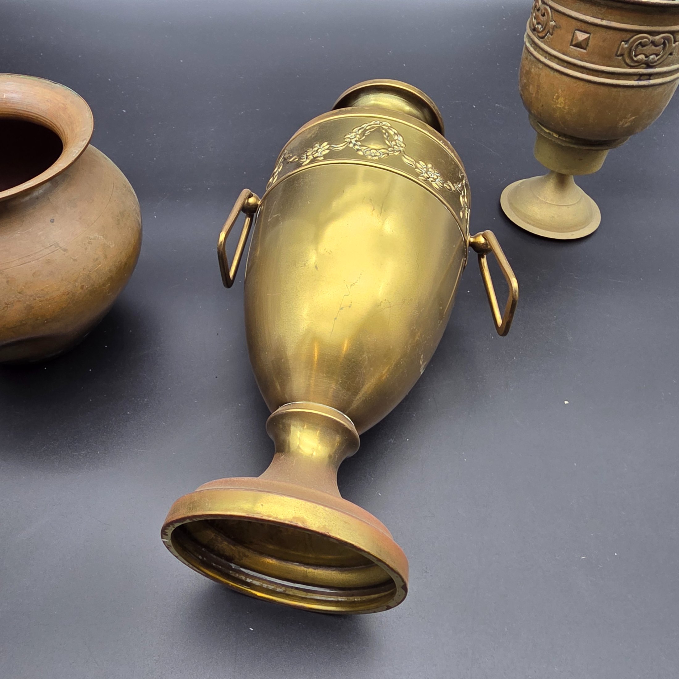 A varied collection of five vintage decorative vessels crafted from brass and copper, including a small footed goblet, a rounded copper pot, a brass bucket with a handle, a tall handled brass urn, and a footed brass goblet with ornate banding. At least one piece bears a 'MADE IN INDIA' label, indicating a probable origin for the entire group. - View 8