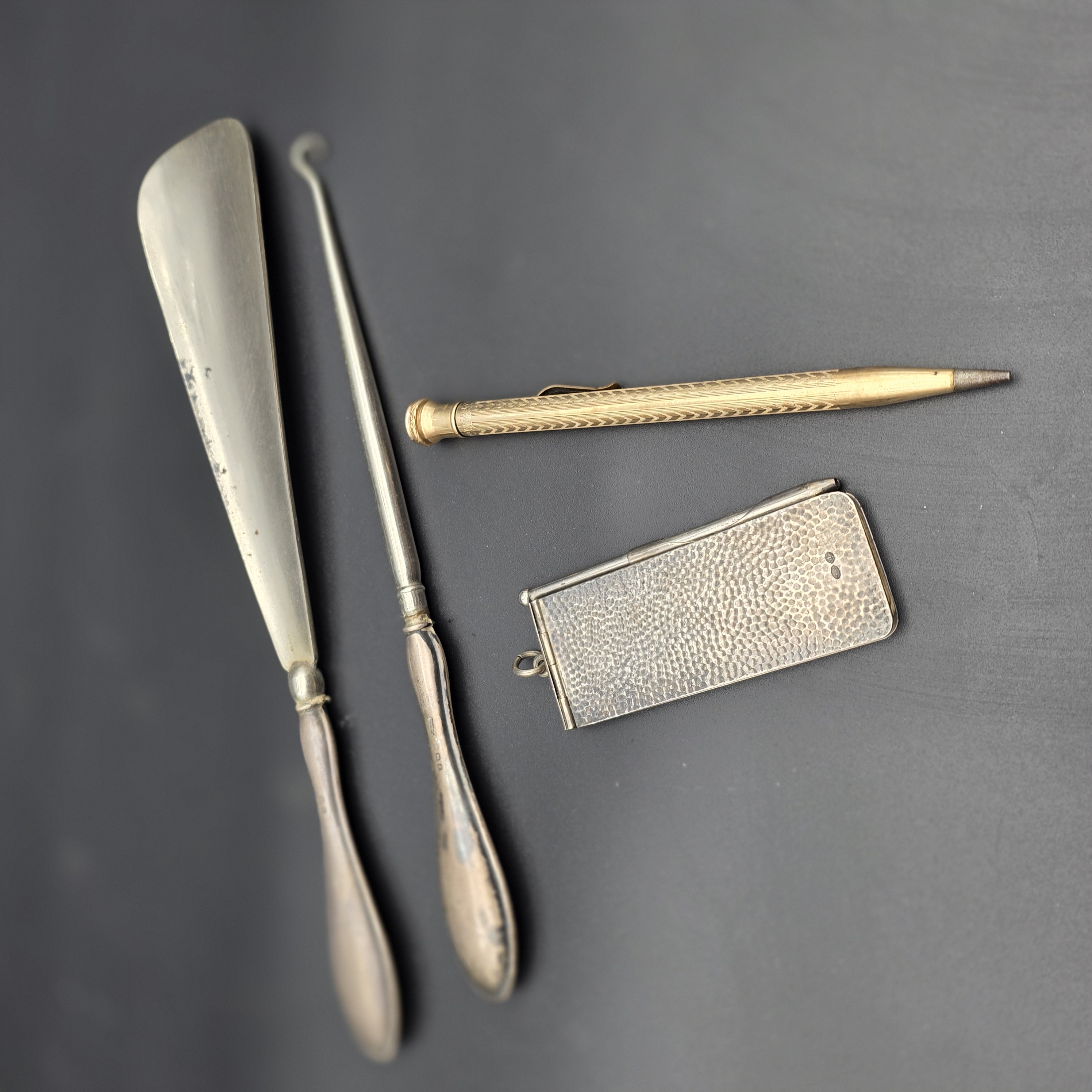 An intriguing collection of early 20th-century personal accessories, featuring sterling silver grooming tools and a notepad, alongside a classic gold-filled mechanical pencil.