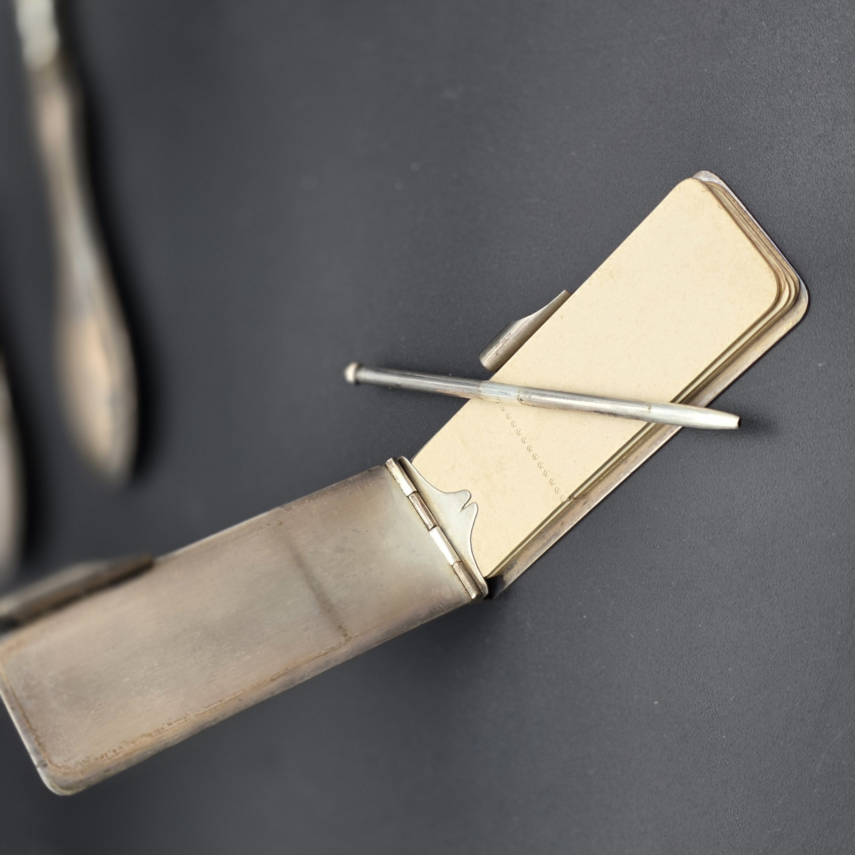 An intriguing collection of early 20th-century personal accessories, featuring sterling silver grooming tools and a notepad, alongside a classic gold-filled mechanical pencil. - View 4