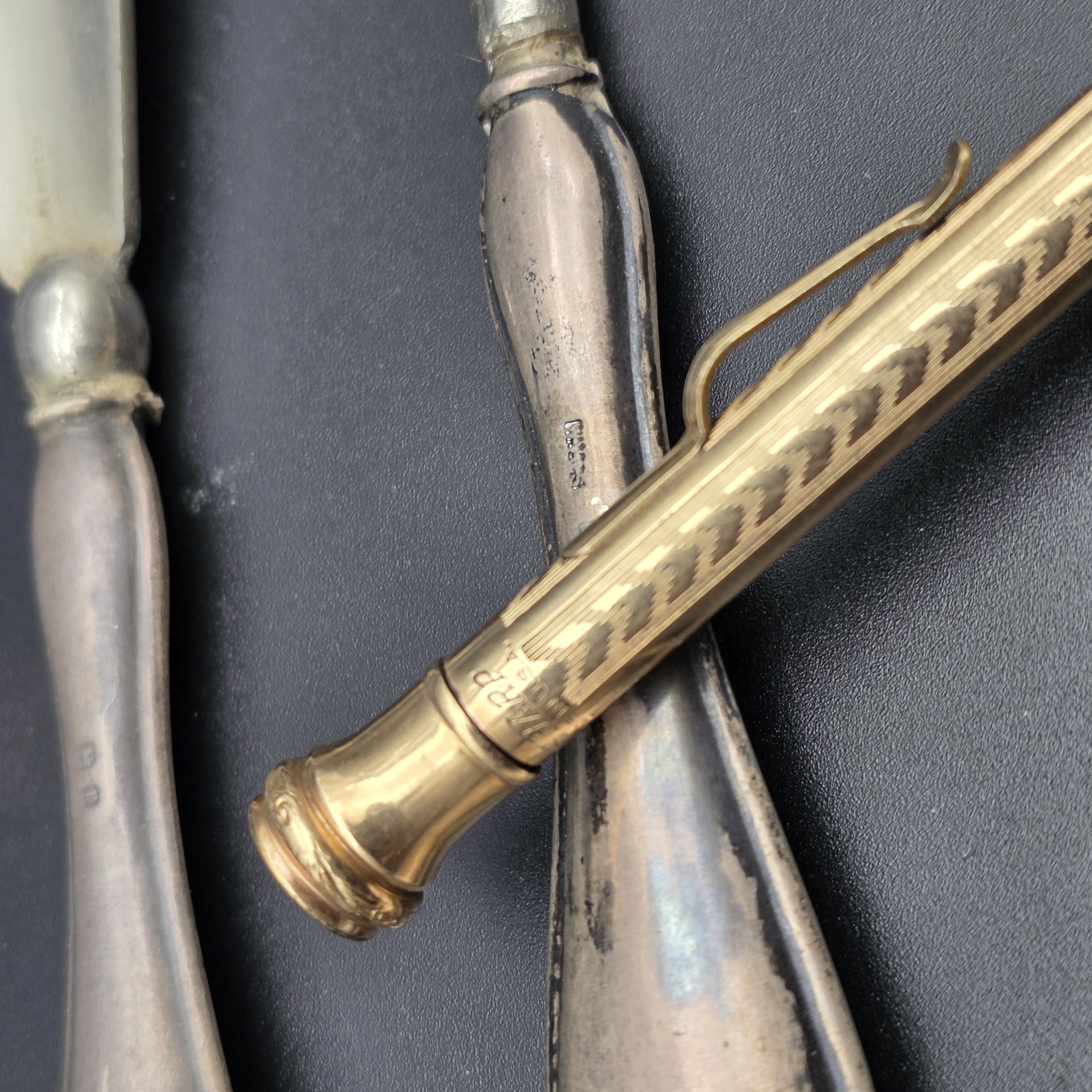 An intriguing collection of early 20th-century personal accessories, featuring sterling silver grooming tools and a notepad, alongside a classic gold-filled mechanical pencil. - View 6