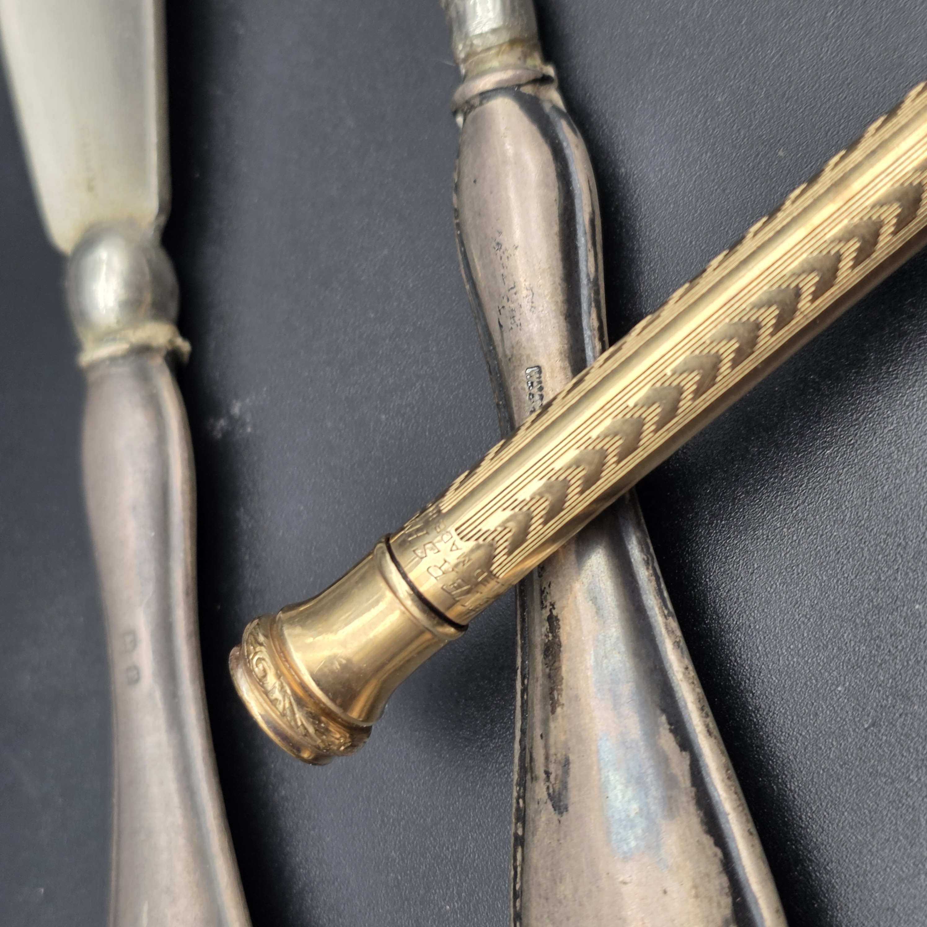 An intriguing collection of early 20th-century personal accessories, featuring sterling silver grooming tools and a notepad, alongside a classic gold-filled mechanical pencil. - View 7