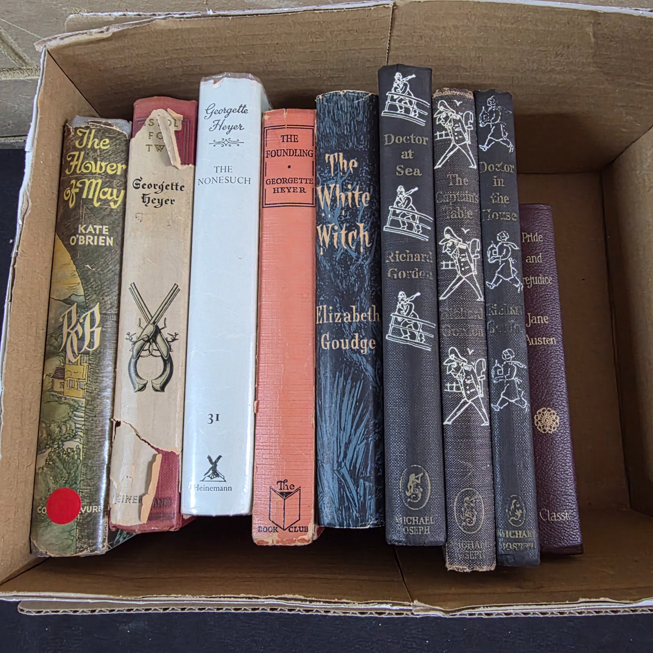 A diverse collection of vintage hardcover novels, including works by prominent authors like Georgette Heyer, Richard Gordon, and Jane Austen, predominantly from the mid-20th century.