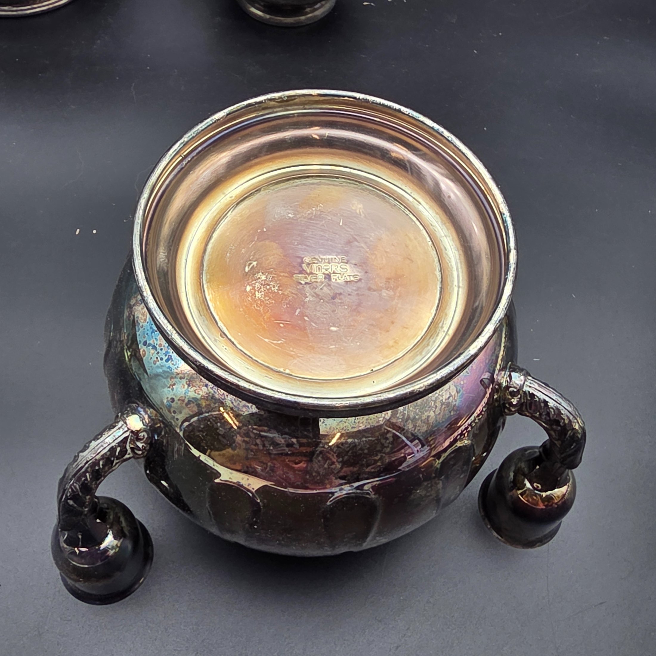A varied collection of vintage silver-plated items including a butter dish, vase, creamer, bowls, and a toast rack, showing signs of heavy tarnishing and wear. - View 5