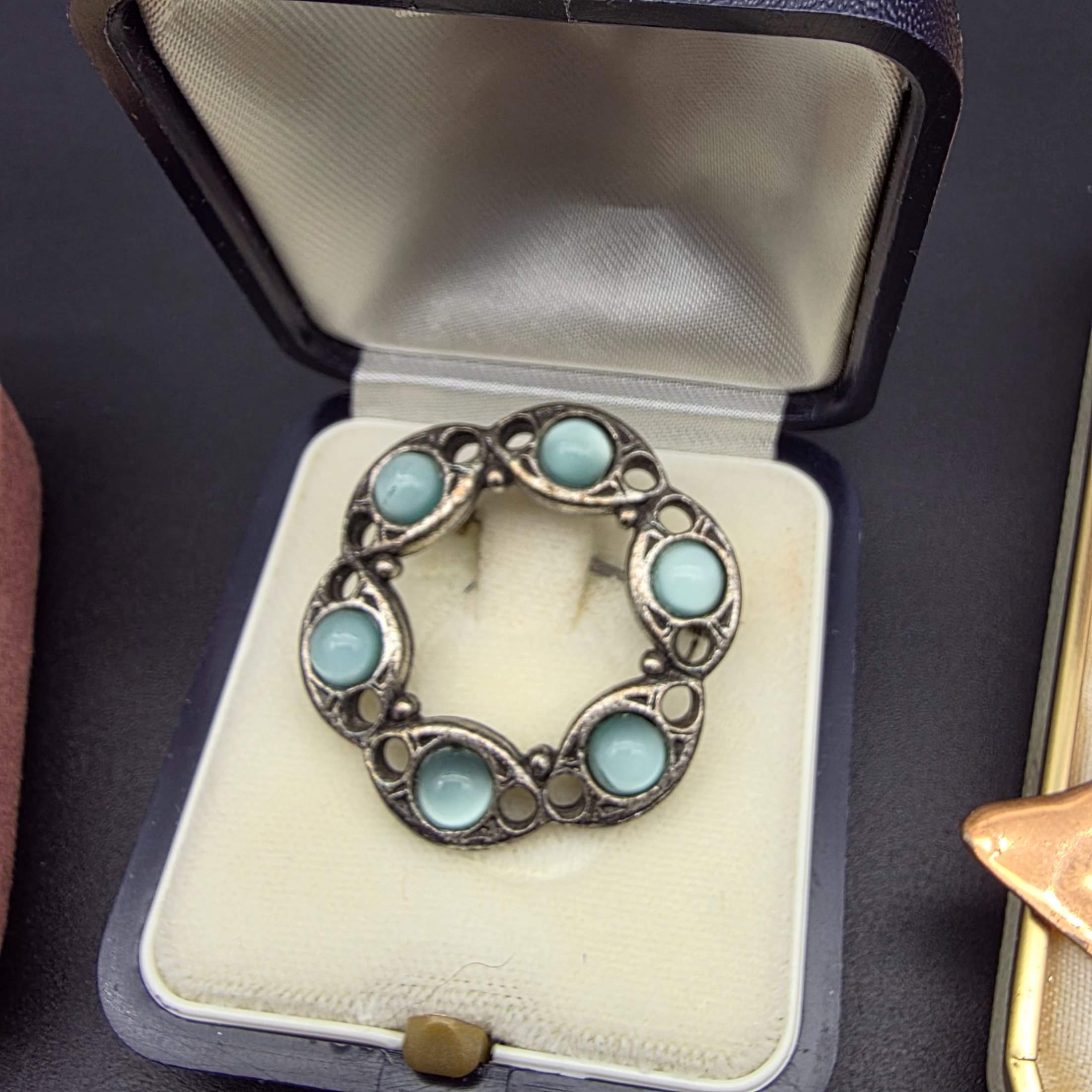 A diverse collection of vintage and sterling silver jewellery, including rings, brooches, necklaces, earrings, and a bangle, displayed across a dark surface. - View 4