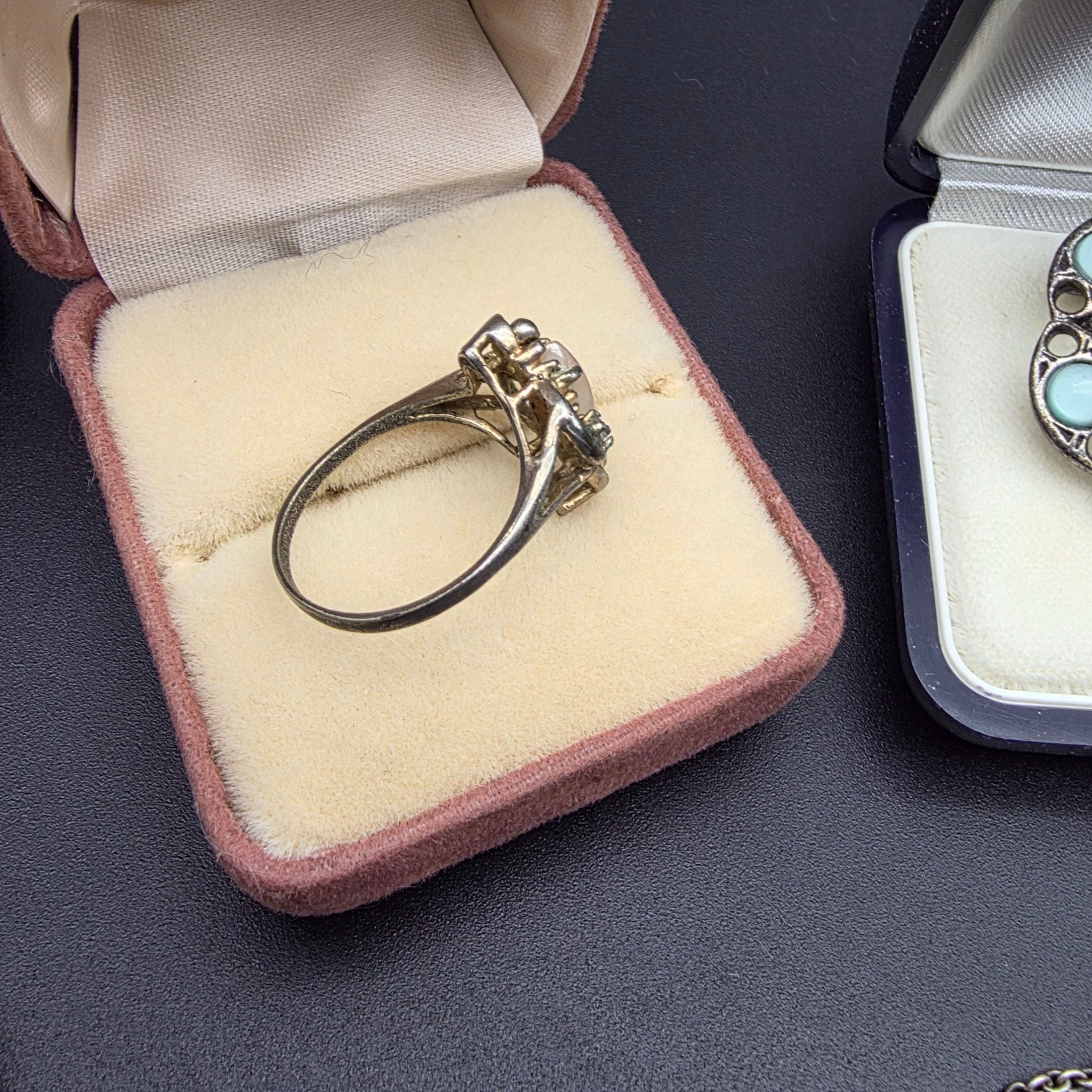 A diverse collection of vintage and sterling silver jewellery, including rings, brooches, necklaces, earrings, and a bangle, displayed across a dark surface. - View 7