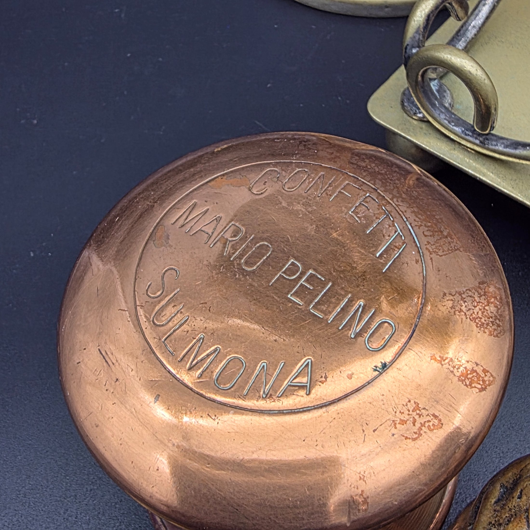 A diverse collection of vintage decorative items crafted from brass and copper, including a tall vase, various ashtrays, a small handled tray, a bell, a letter opener, and other small metallic objects, likely from the mid-20th century. - View 3