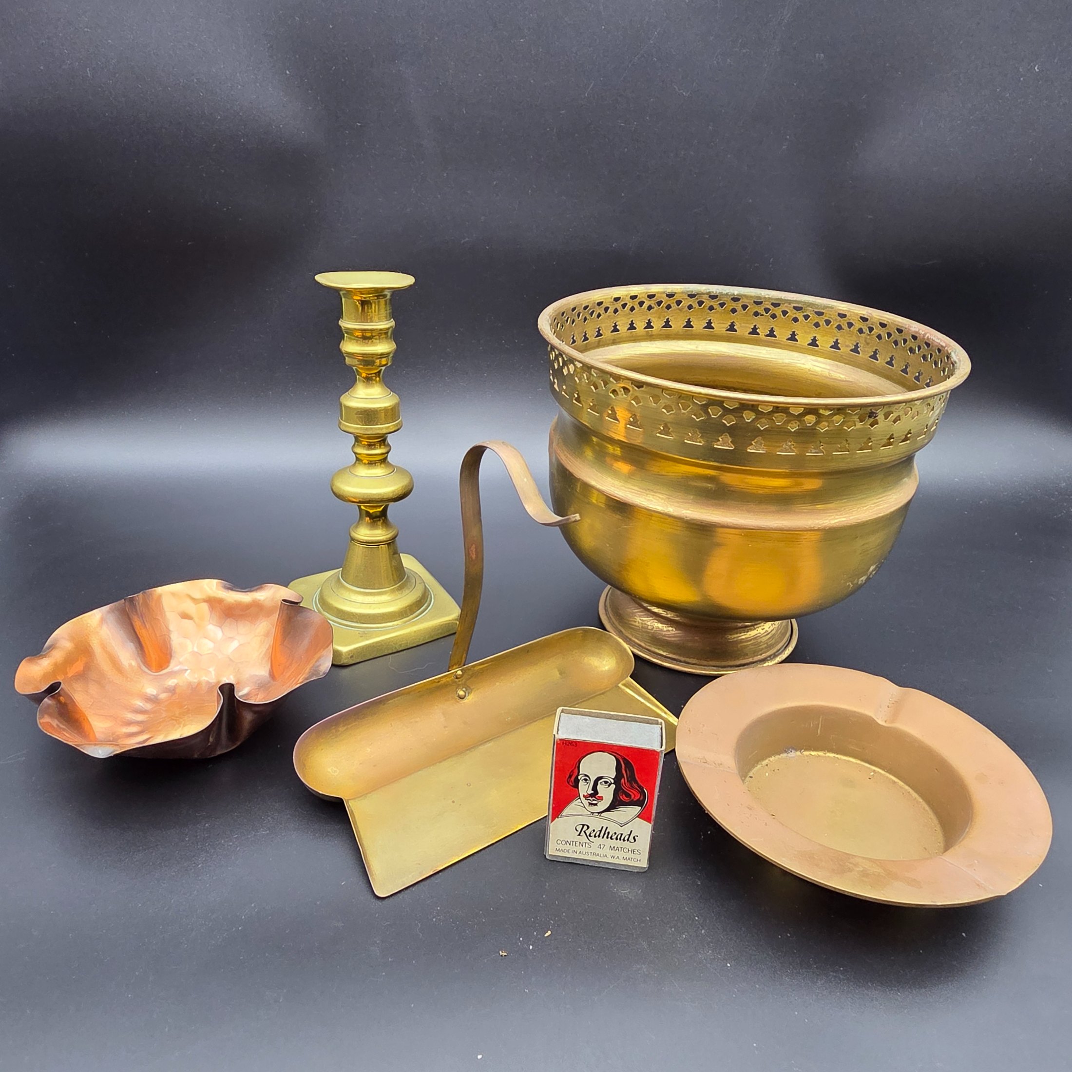 A collection of vintage metal home decor and utility items, featuring brass and copper pieces from the mid-20th century, including a planter, candlestick, crumb tray, copper dish, and ashtray.