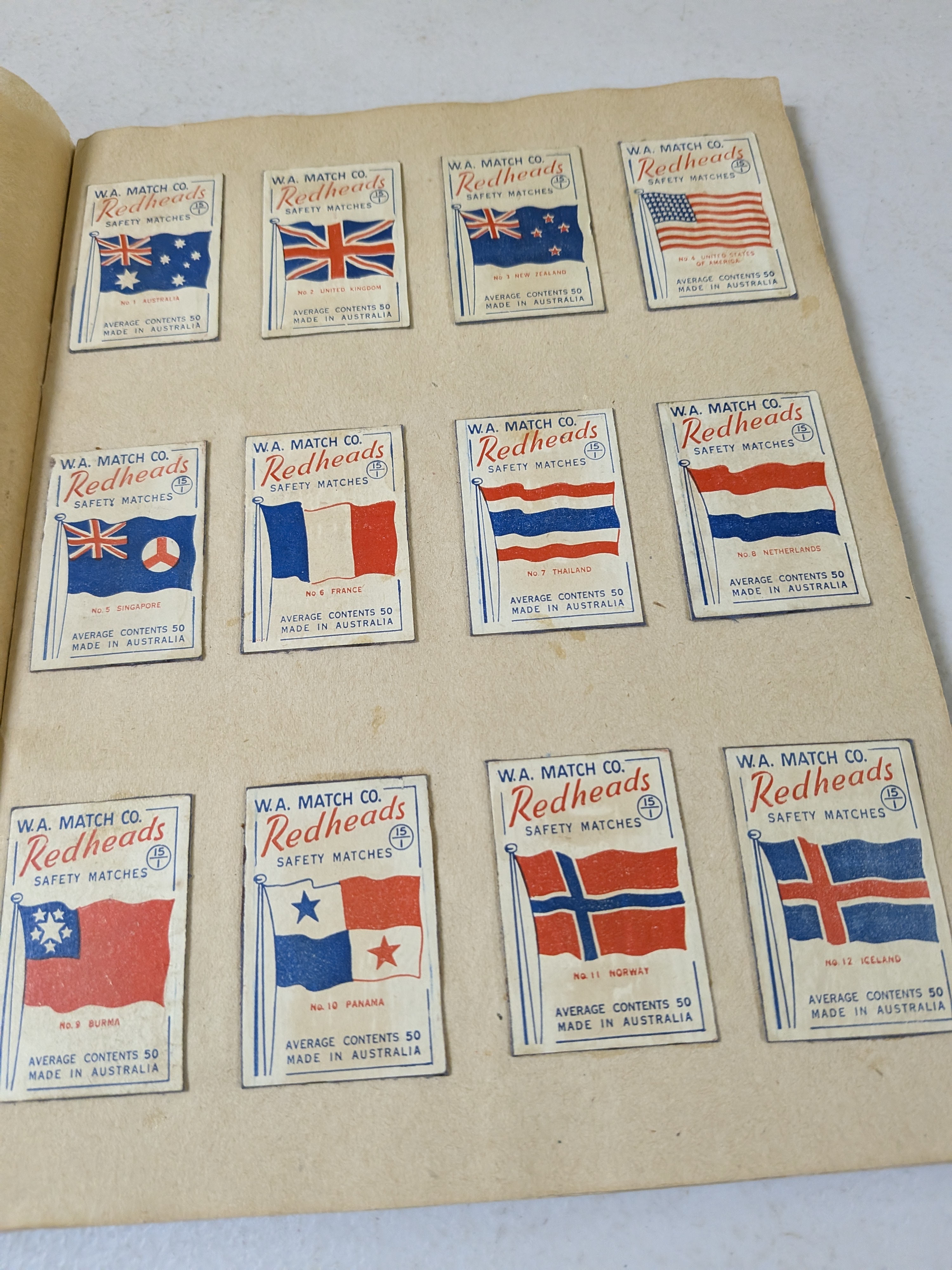 An album containing a collection of vintage Redheads Safety Matches labels, produced by W.A. Match Co. in Australia, showcasing various series including international flags and Australian fauna.