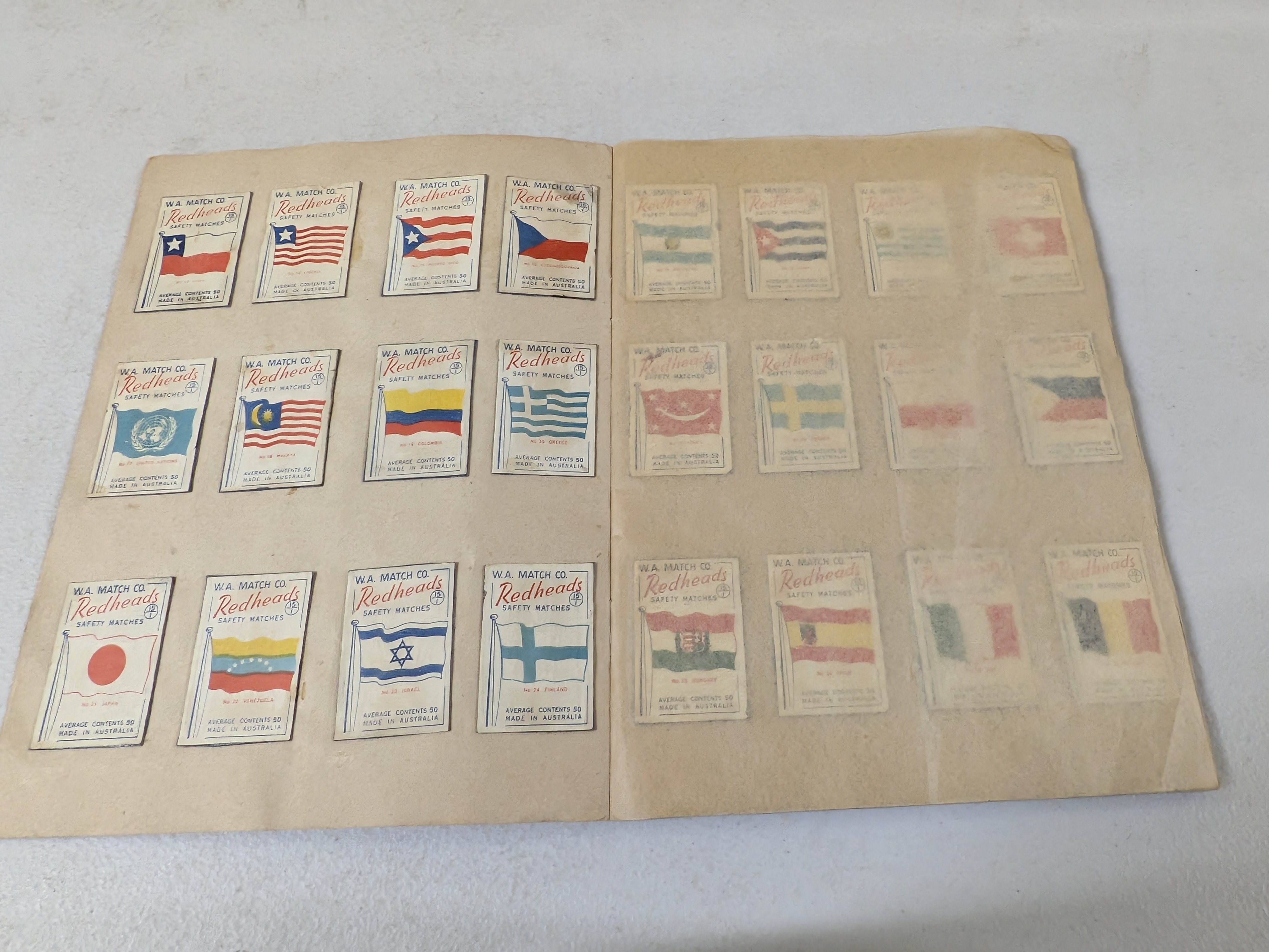 An album containing a collection of vintage Redheads Safety Matches labels, produced by W.A. Match Co. in Australia, showcasing various series including international flags and Australian fauna. - View 2