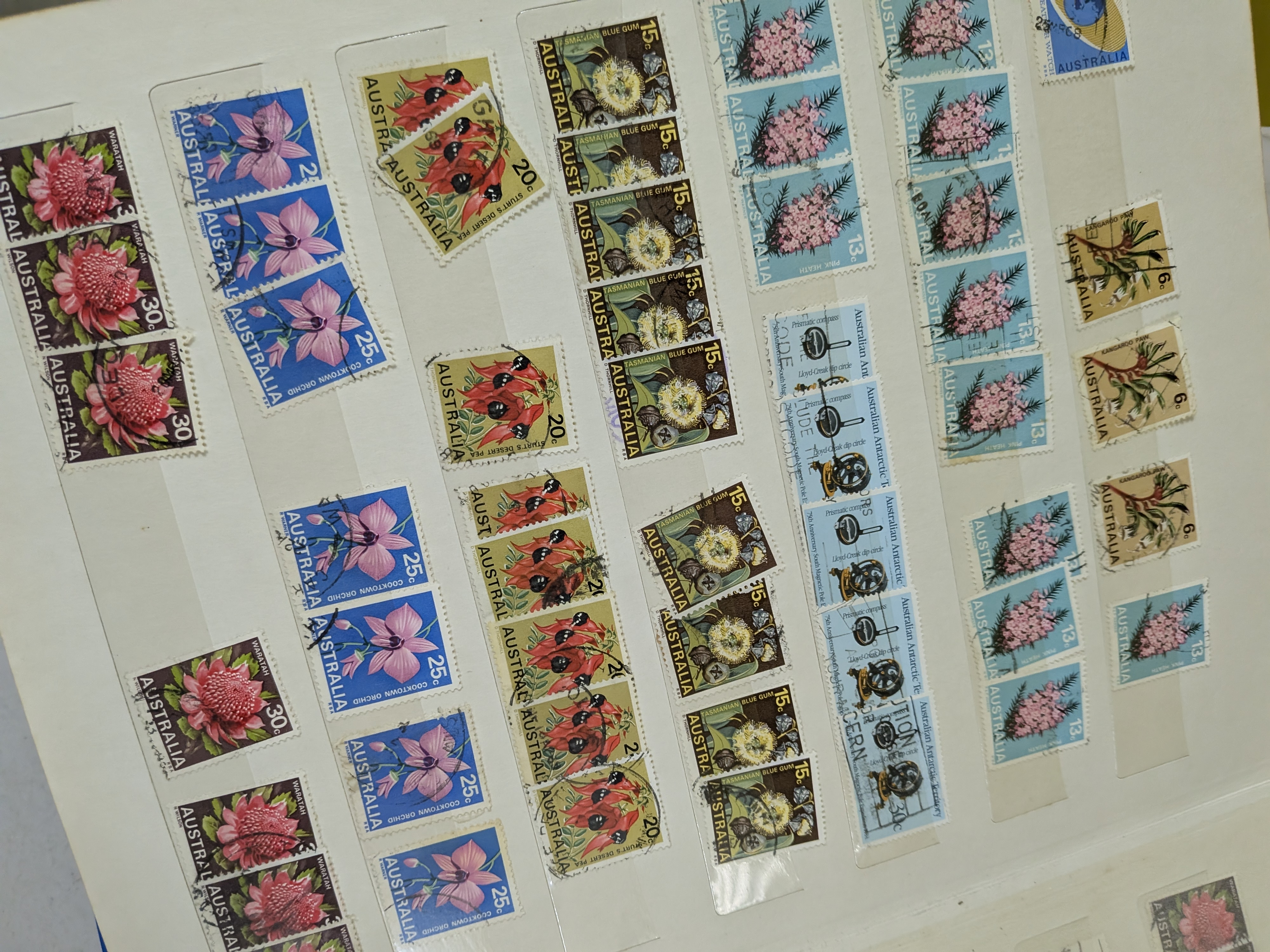A collection of four vintage stamp albums, filled with Australian postage stamps predominantly from the mid to late 20th century, presented in various states of completion. - View 2