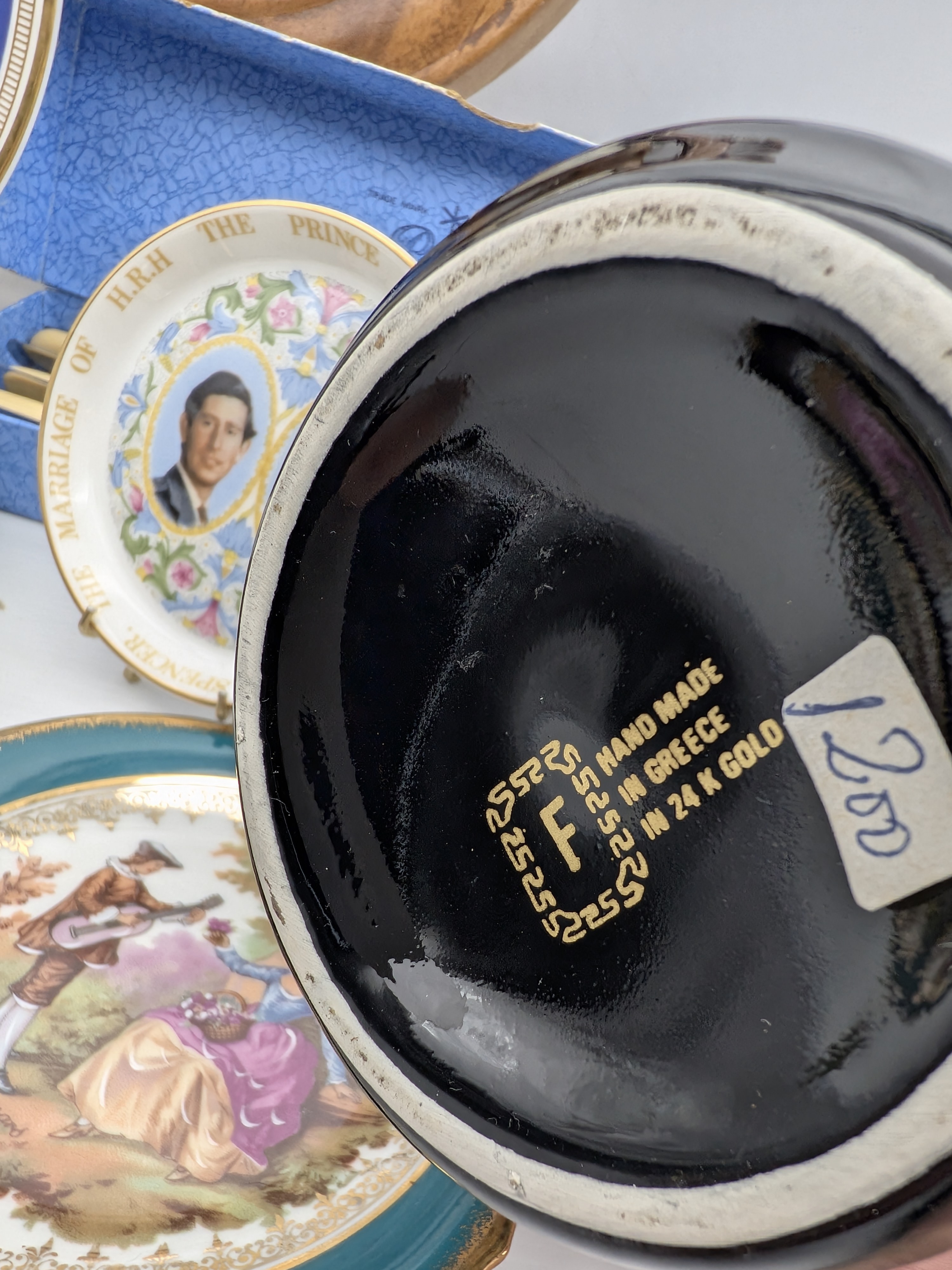 A diverse collection of vintage homewares and decorative sundries, including ceramic plates, a Greek-style amphora with lid, and a nautical-themed barometer/thermometer on a ship's wheel. - View 3
