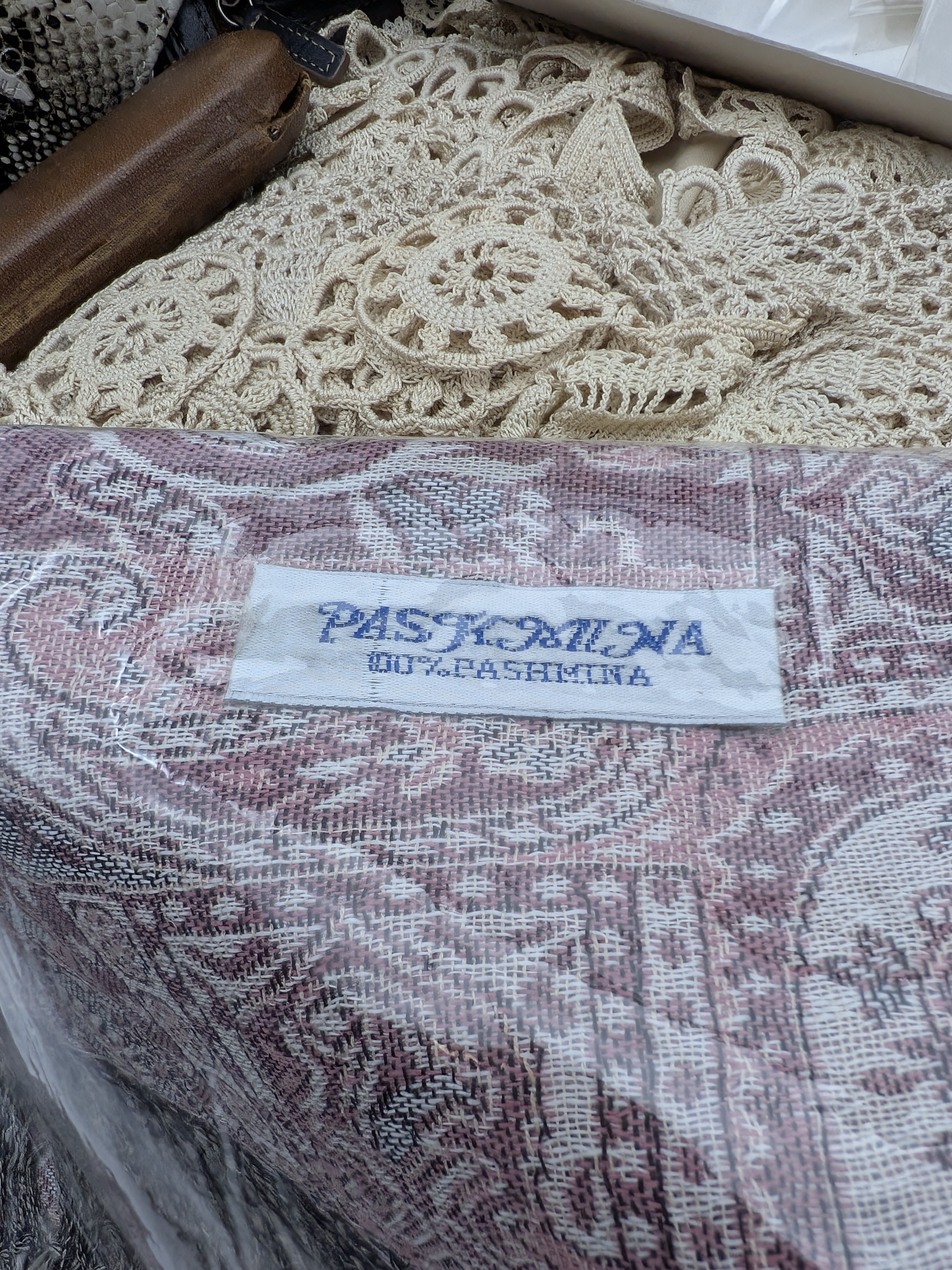A diverse collection of vintage and contemporary household and personal accessories, including textile goods such as embroidered handkerchiefs, a pure pashmina shawl, and a quantity of crocheted lace, alongside several small leather and fabric purses and a spectacle case. - View 5