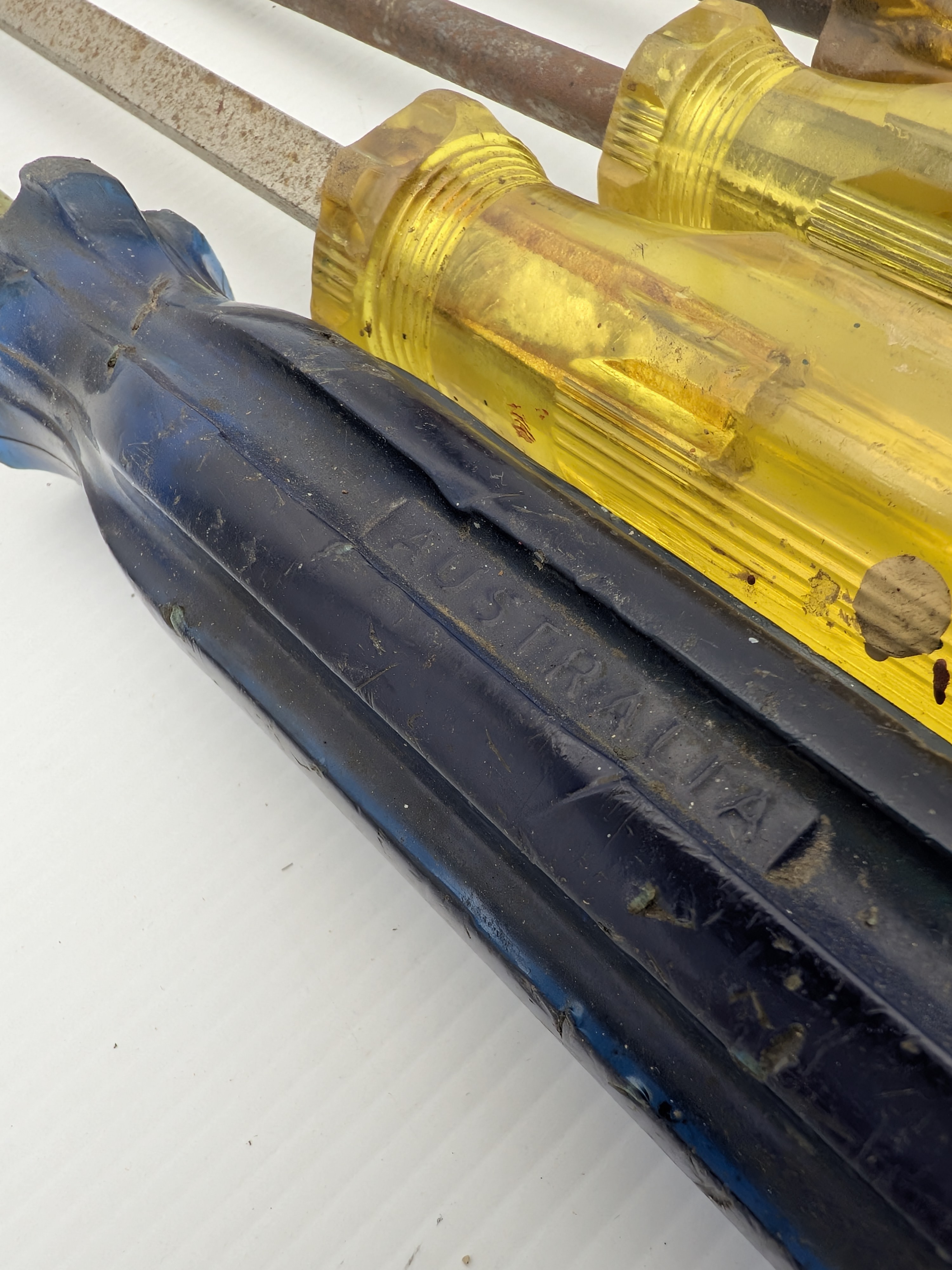 A collection of vintage hand tools including various sizes of Stanley screwdrivers with colored plastic handles and Sidchrome wrenches, showing signs of heavy use and age. - View 4