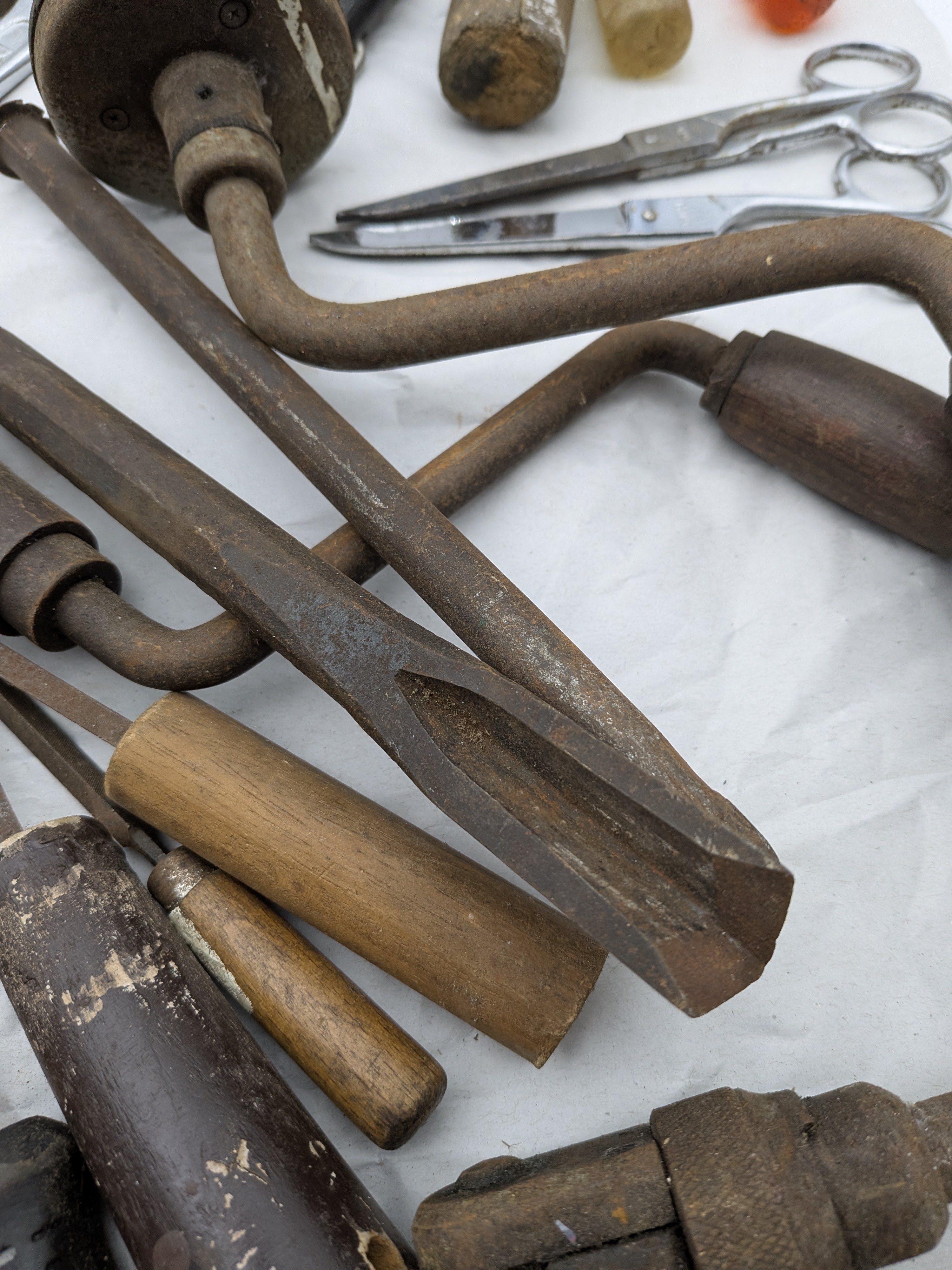 A large collection of assorted vintage hand tools, including various saws, files, chisels, wrenches, pliers, screwdrivers, and drills, exhibiting extensive surface rust and wear. - View 5