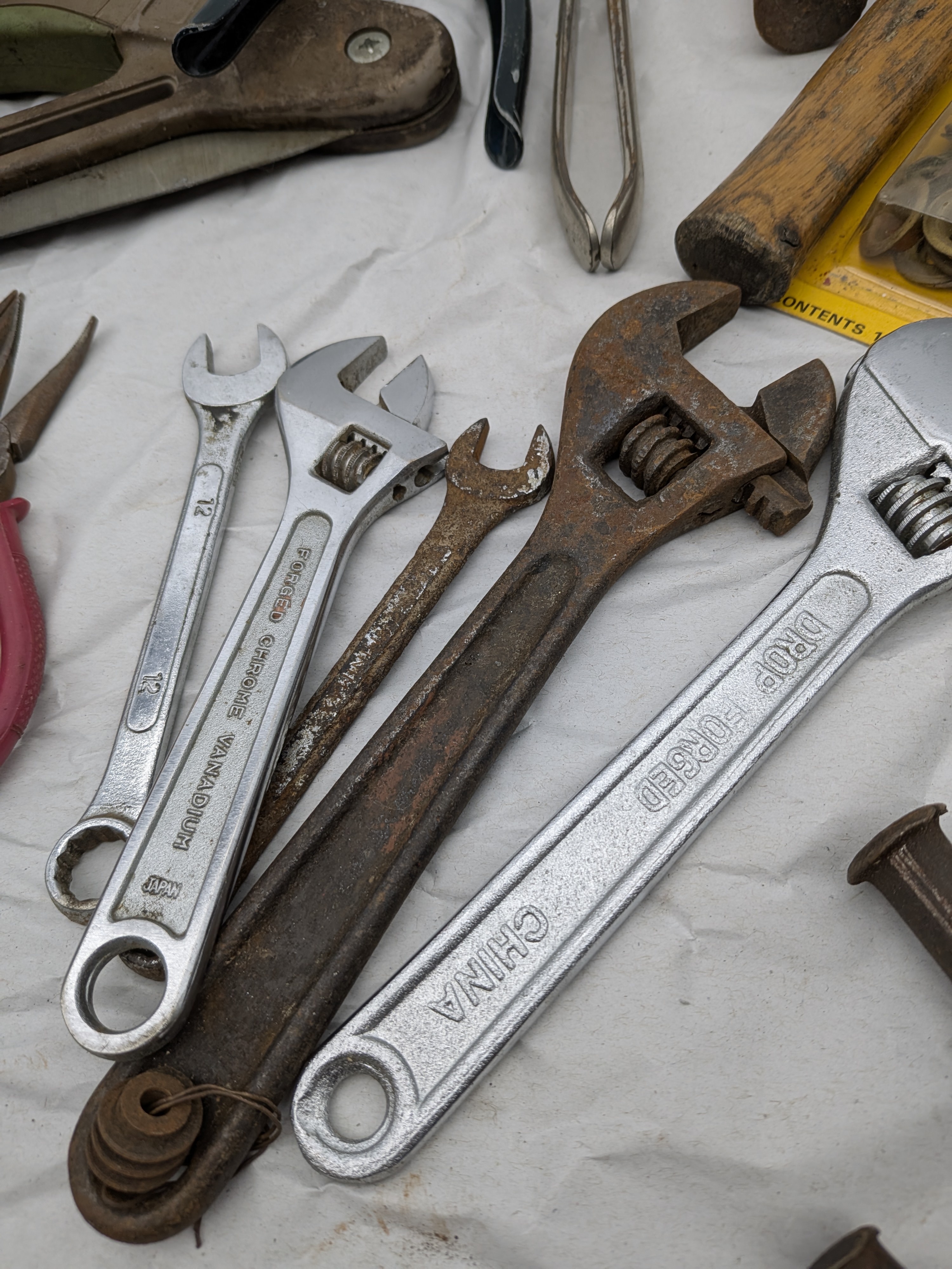 A large collection of assorted vintage hand tools, including various saws, files, chisels, wrenches, pliers, screwdrivers, and drills, exhibiting extensive surface rust and wear. - View 7