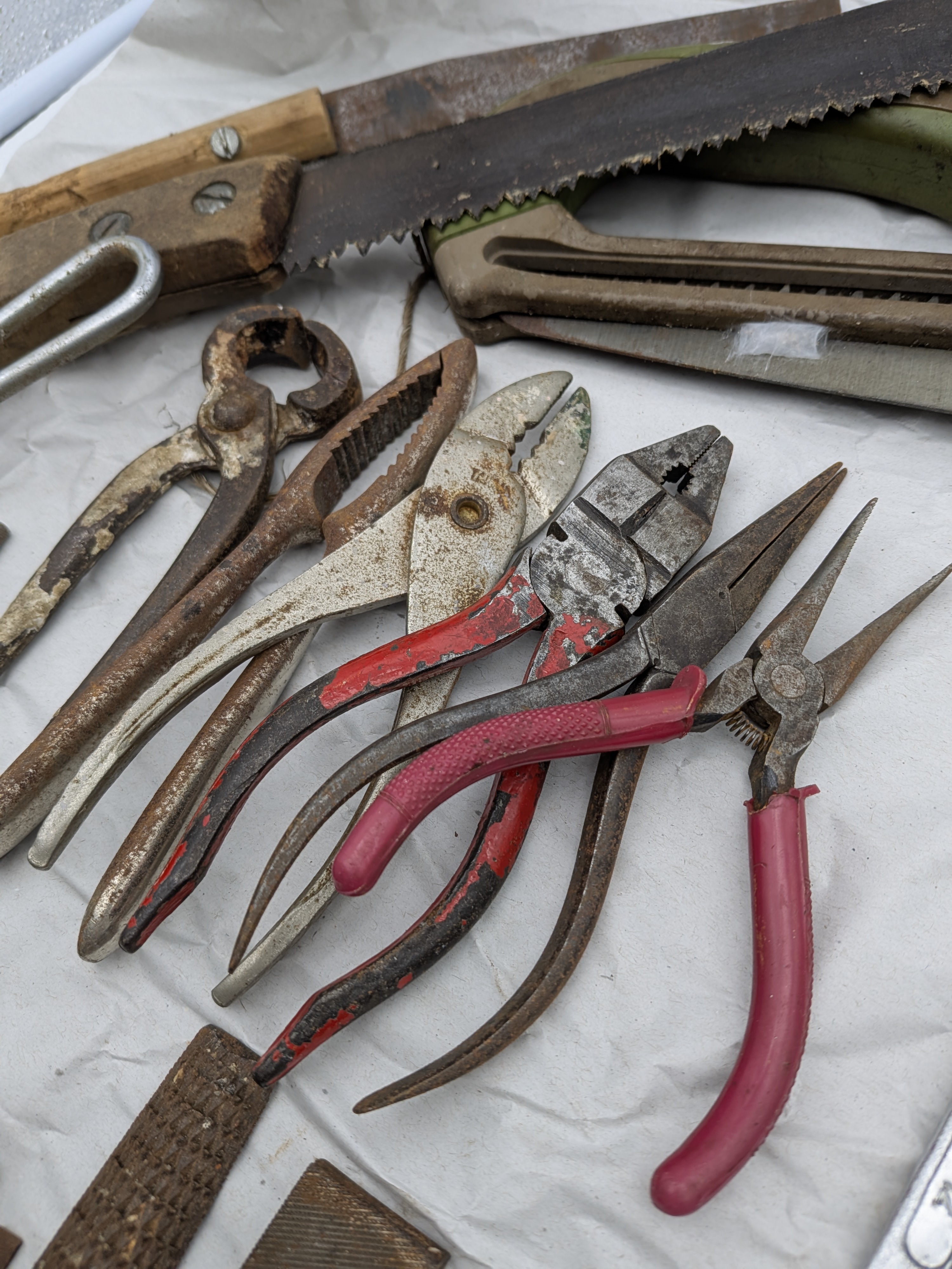 A large collection of assorted vintage hand tools, including various saws, files, chisels, wrenches, pliers, screwdrivers, and drills, exhibiting extensive surface rust and wear. - View 8