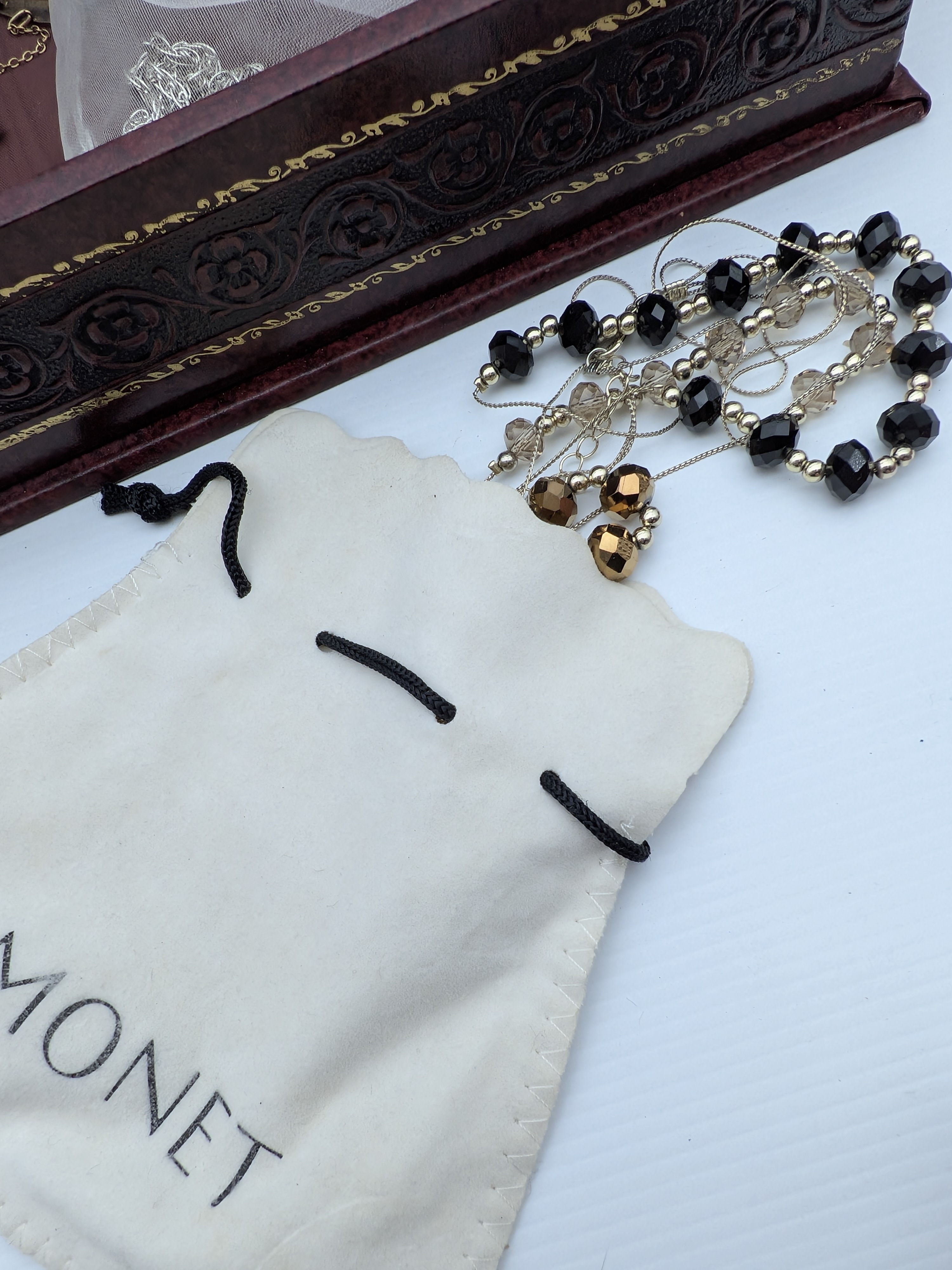 An assortment of costume jewellery and watches, spanning various styles and eras, presented across two plastic storage containers, a decorative red velvet-covered box, and includes a 'Monet' branded pouch. - View 8