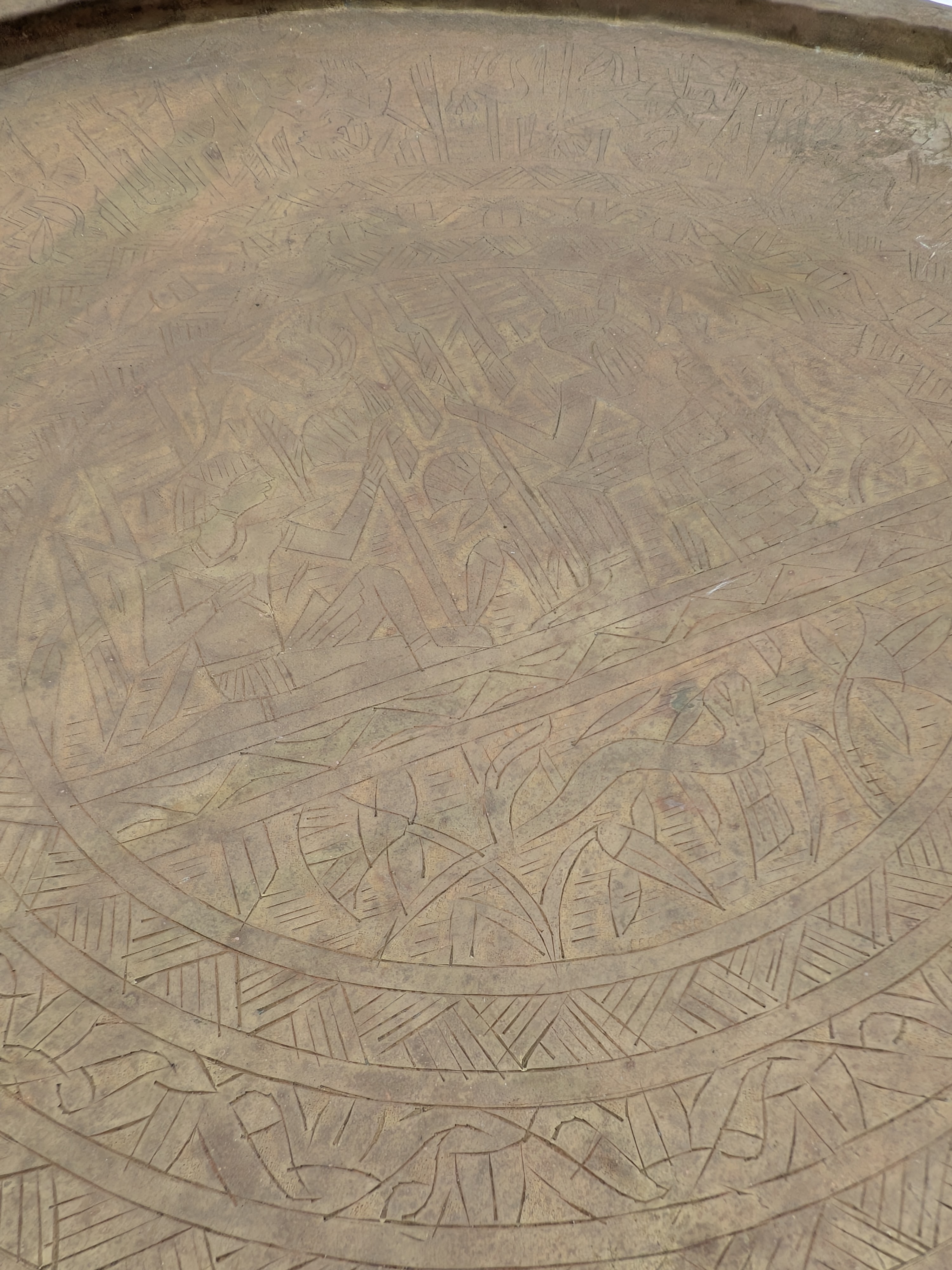 A substantial vintage etched brass tray, likely from the mid-20th century, showcasing traditional Middle Eastern or North African decorative metalwork. Its broad, circular form features intricate, deeply etched patterns across its surface, including figural elements, geometric motifs, and possibly calligraphic designs, characteristic of artisan craftsmanship from the region. - View 3