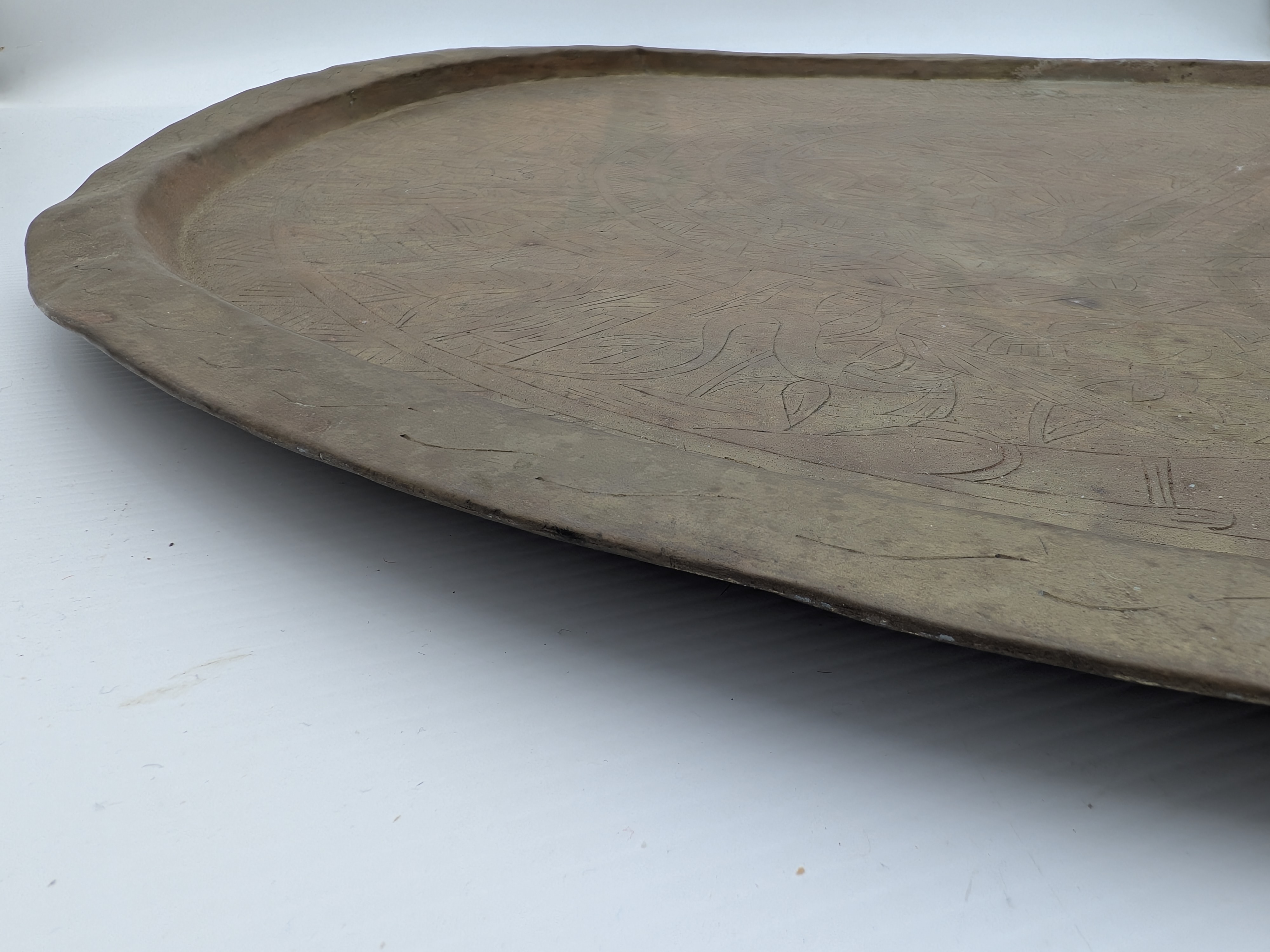 A substantial vintage etched brass tray, likely from the mid-20th century, showcasing traditional Middle Eastern or North African decorative metalwork. Its broad, circular form features intricate, deeply etched patterns across its surface, including figural elements, geometric motifs, and possibly calligraphic designs, characteristic of artisan craftsmanship from the region. - View 4