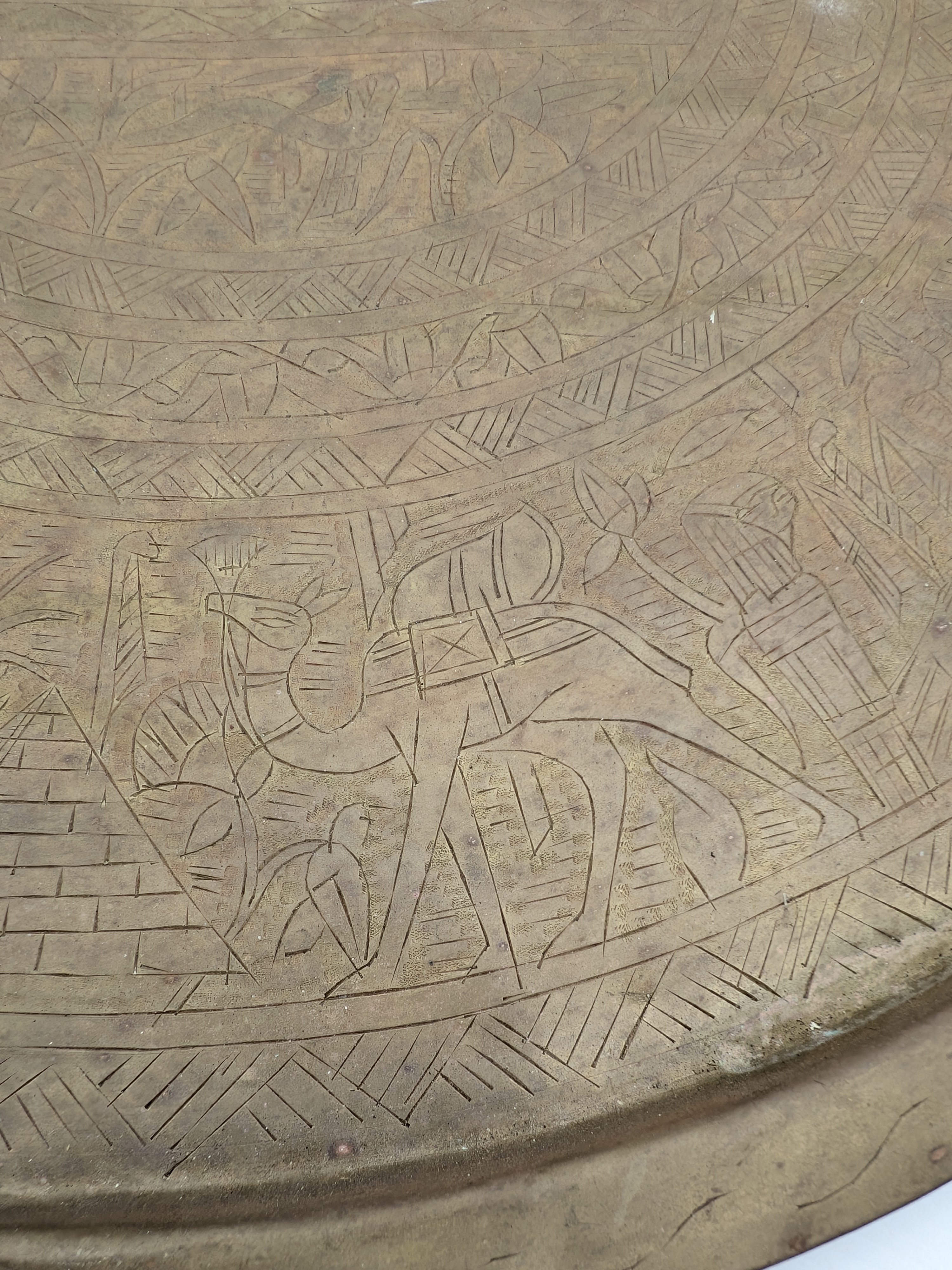 A substantial vintage etched brass tray, likely from the mid-20th century, showcasing traditional Middle Eastern or North African decorative metalwork. Its broad, circular form features intricate, deeply etched patterns across its surface, including figural elements, geometric motifs, and possibly calligraphic designs, characteristic of artisan craftsmanship from the region. - View 6