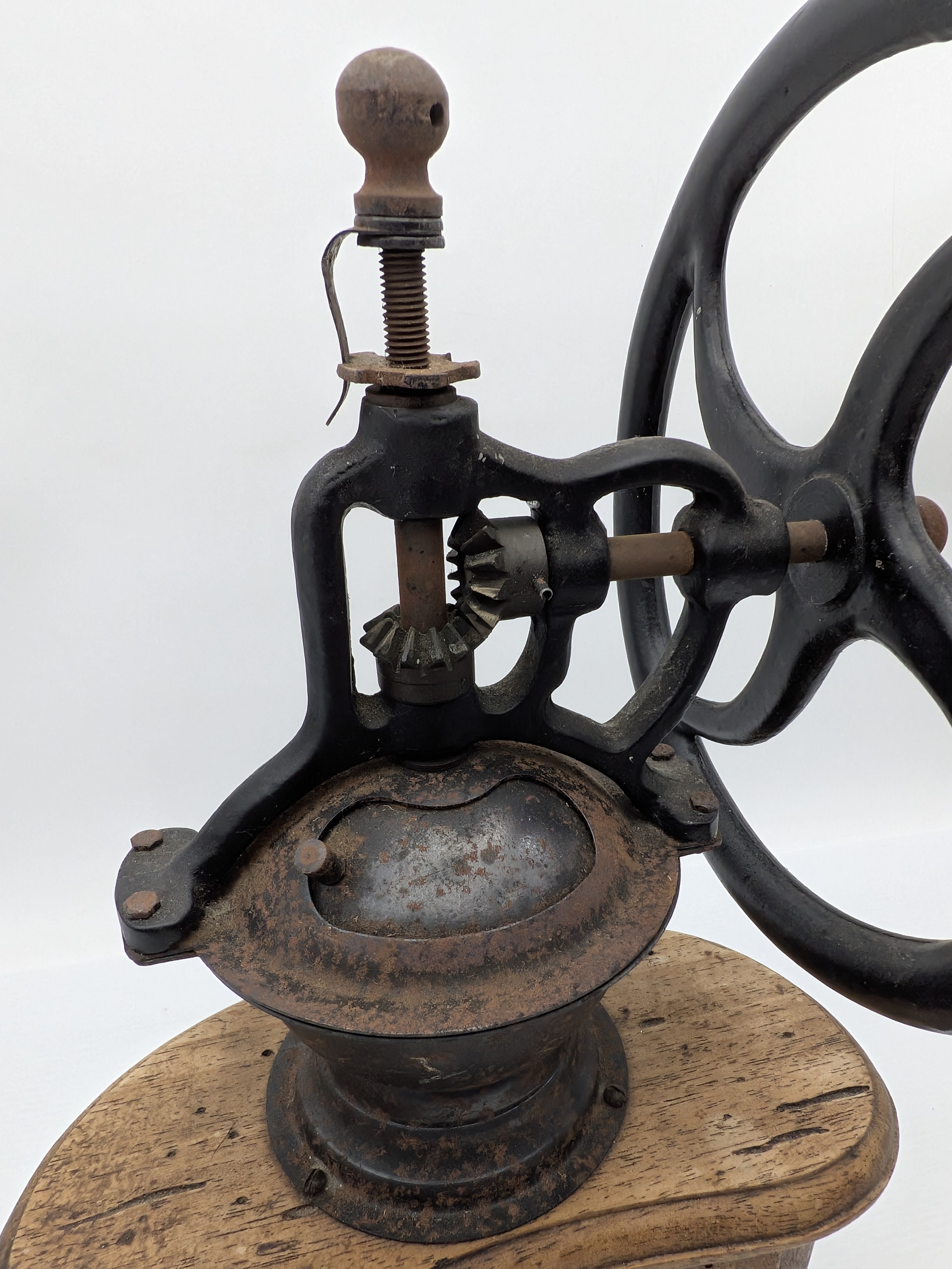 An antique wooden and cast iron hand-crank coffee grinder, featuring a robust iron grinding mechanism with a large flywheel and a solid wooden base housing two small collection drawers. - View 3