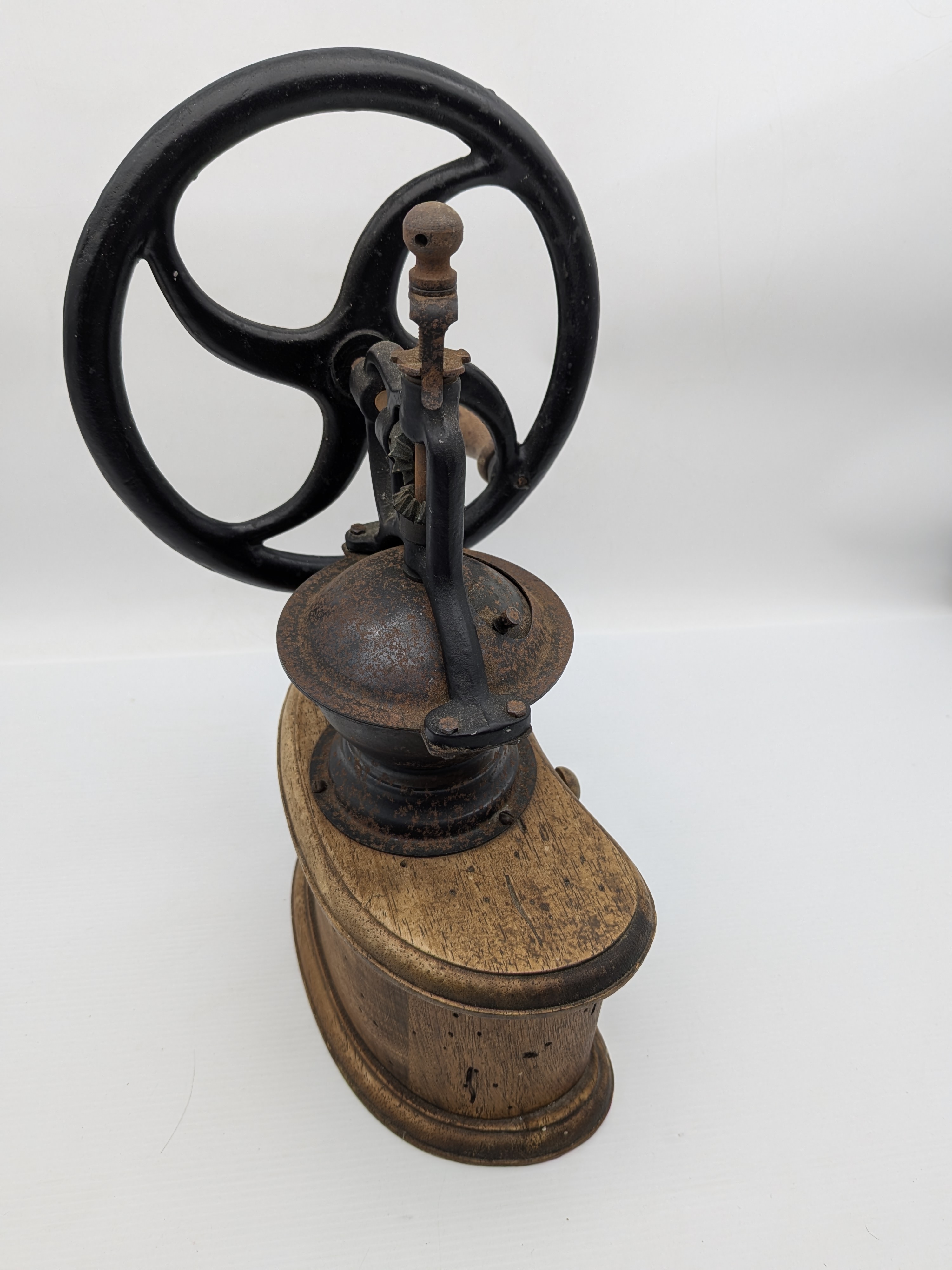 An antique wooden and cast iron hand-crank coffee grinder, featuring a robust iron grinding mechanism with a large flywheel and a solid wooden base housing two small collection drawers. - View 5