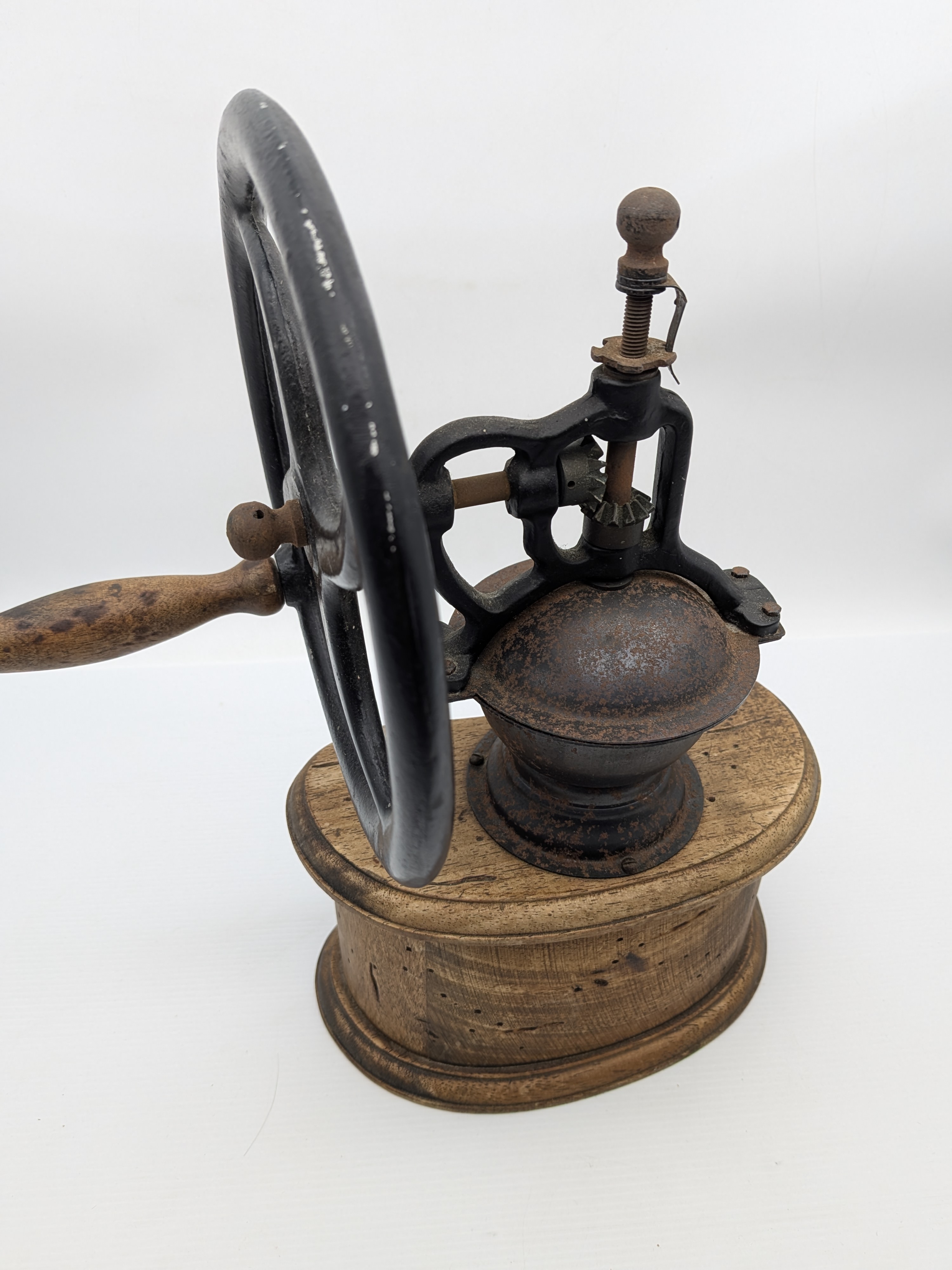 An antique wooden and cast iron hand-crank coffee grinder, featuring a robust iron grinding mechanism with a large flywheel and a solid wooden base housing two small collection drawers. - View 6