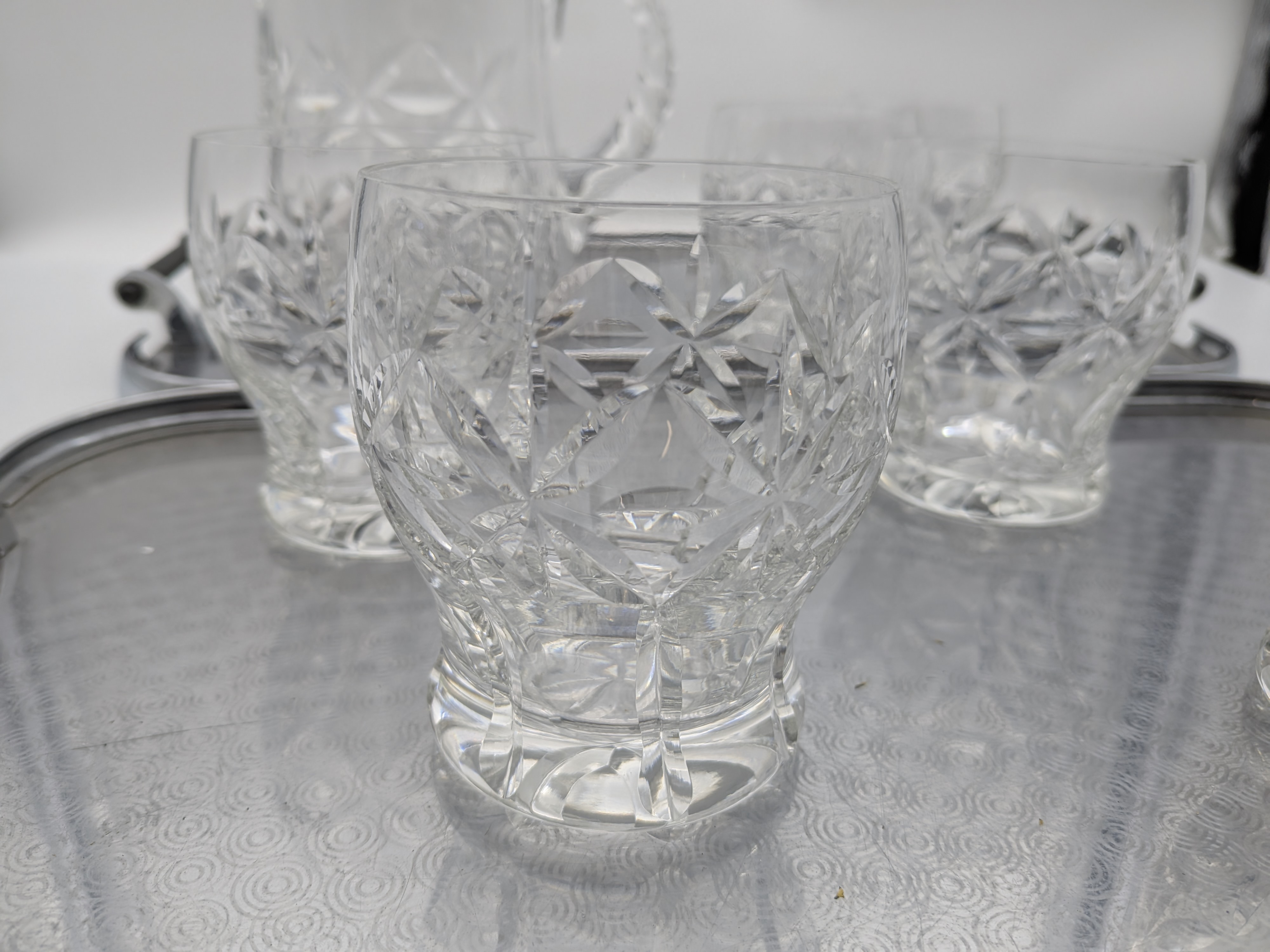 A vintage cut glass pitcher and seven tumblers, accompanied by two silver-plated serving trays, likely from the mid-20th century, showcasing classic barware elegance. - View 2