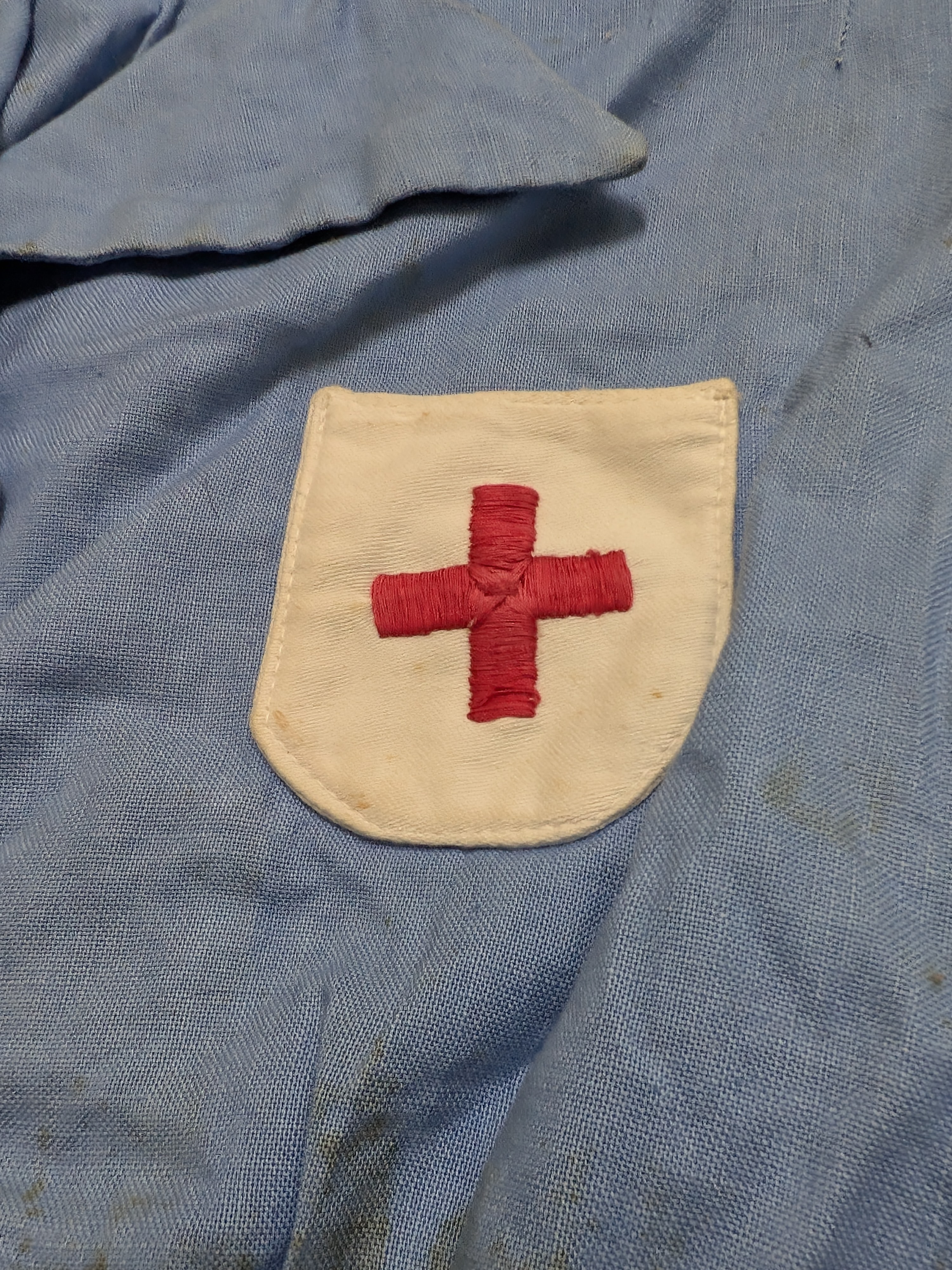 A vintage light blue nurse's uniform dress with a white collar and a red cross emblem, likely from the mid-20th century, made of cotton blend fabric. - View 3