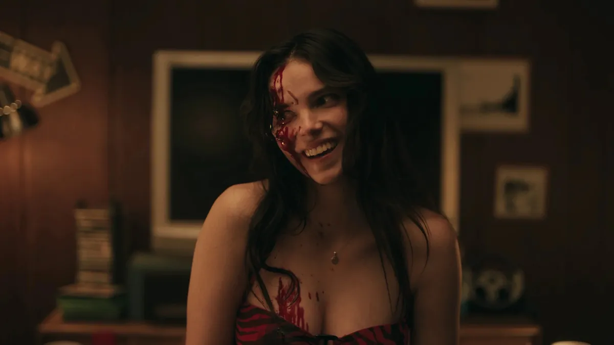 Inde Navarrette as Nikki in Obsession, showing her with a sinister smile and blood on her face
