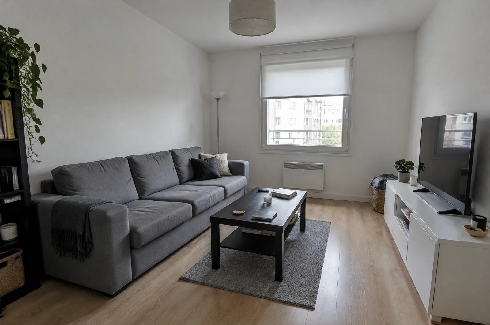 An ordinary apartment living room before any changes: white walls, one window with a roller shade, gray sofa, black coffee table, small gray rug (AI-generated illustration)