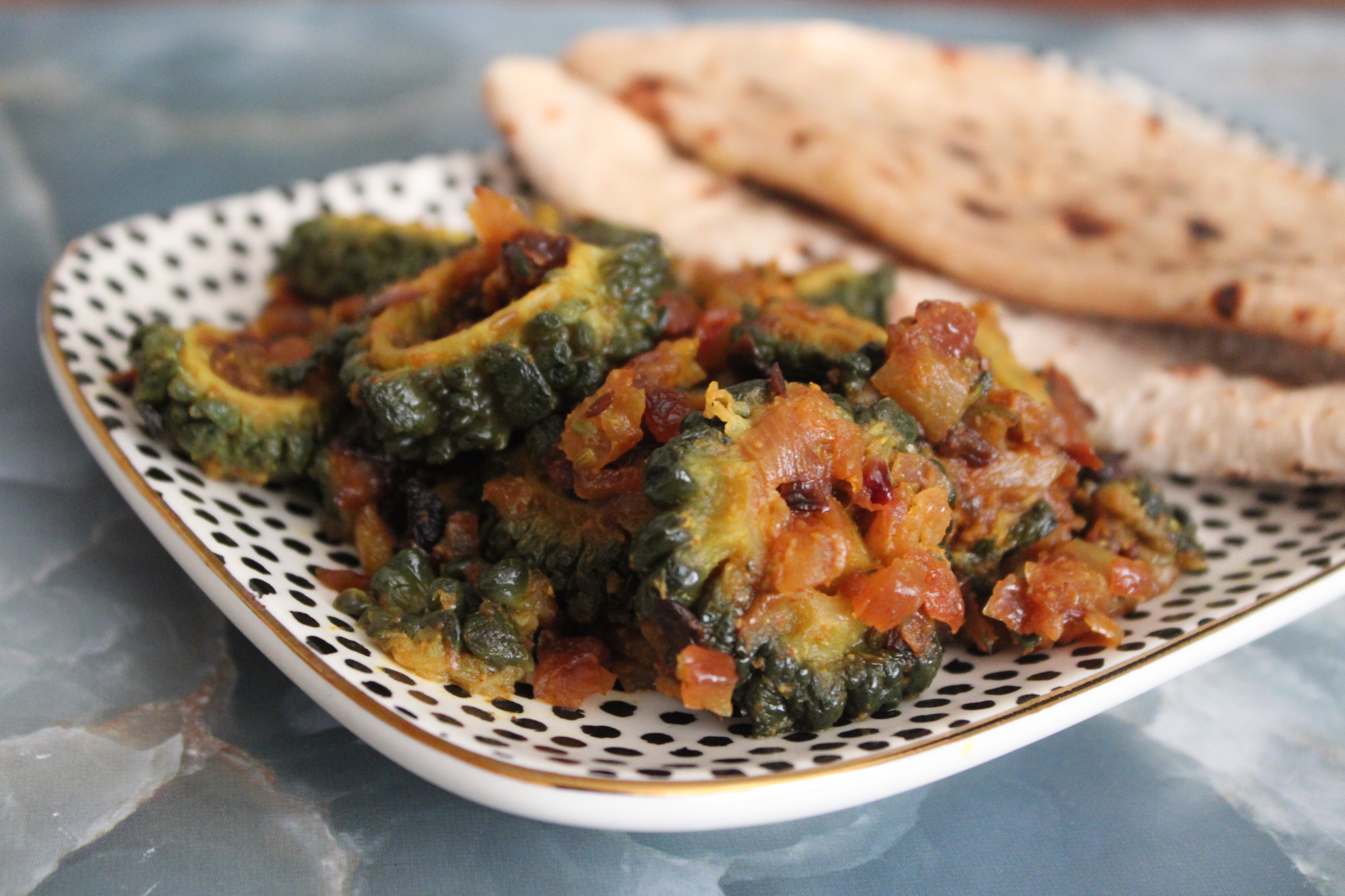 Sautéed bitter gourd rings with golden onions and raw mango chunks