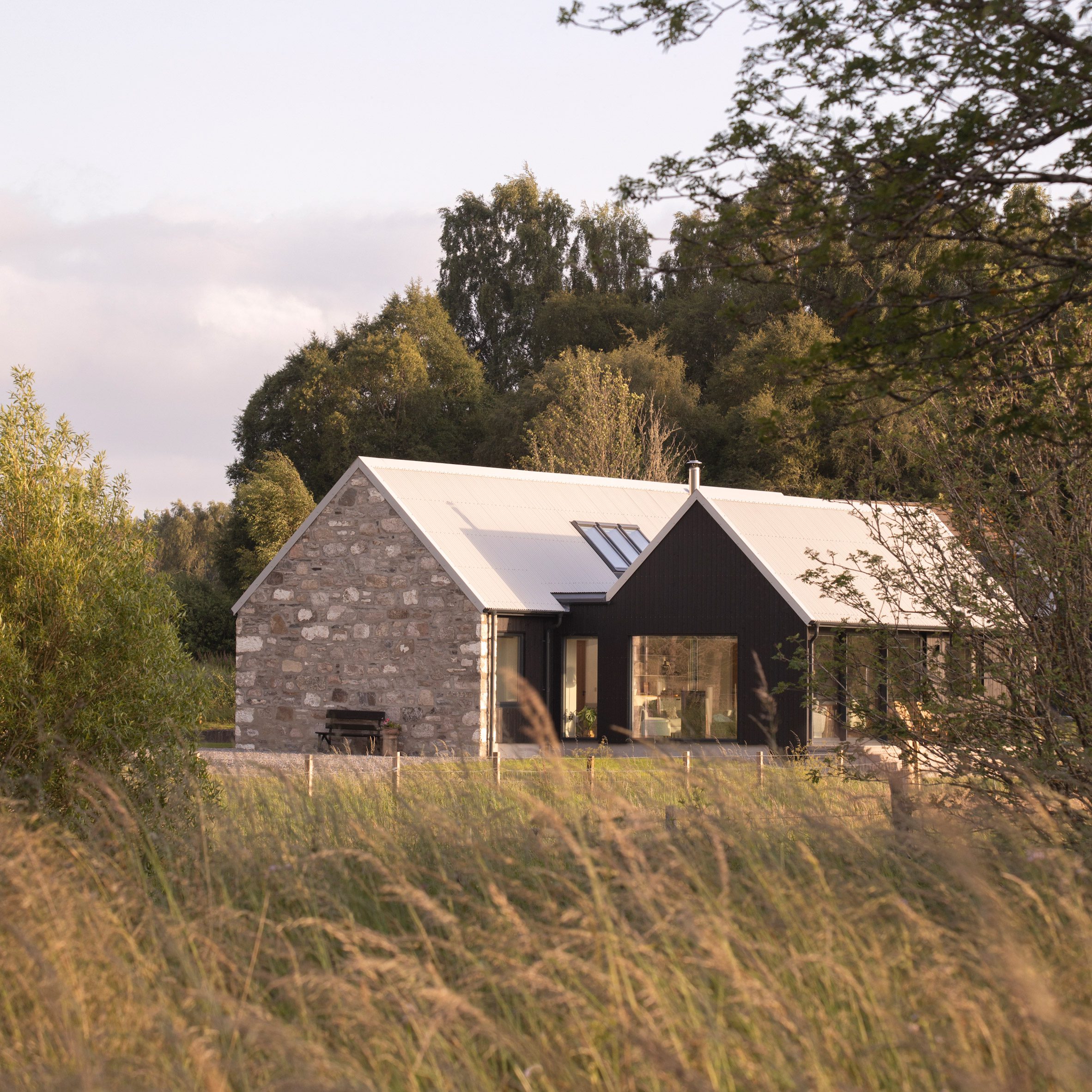 Exterior of Dulnain showing the restored granite cottage beside a blackened-larch extension