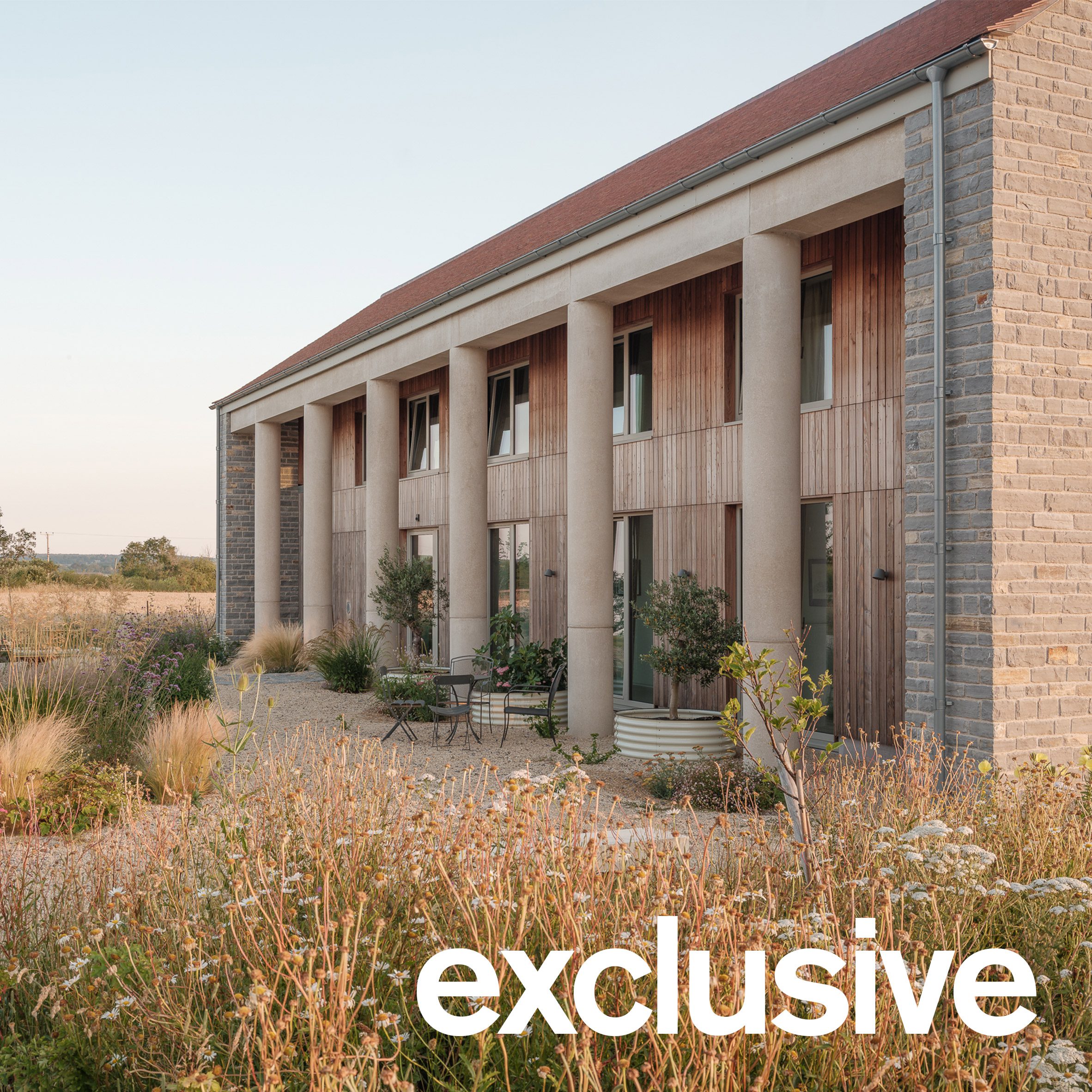 Oblique view along the length of the house showing the row of cylindrical concrete columns and landscaped garden