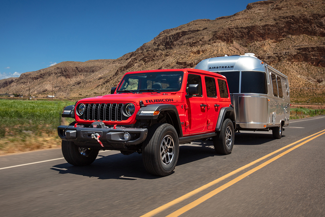 Vue 3/4 avant et latérale du Jeep Wrangler Rubicon 2024 sur route avec remorque VR