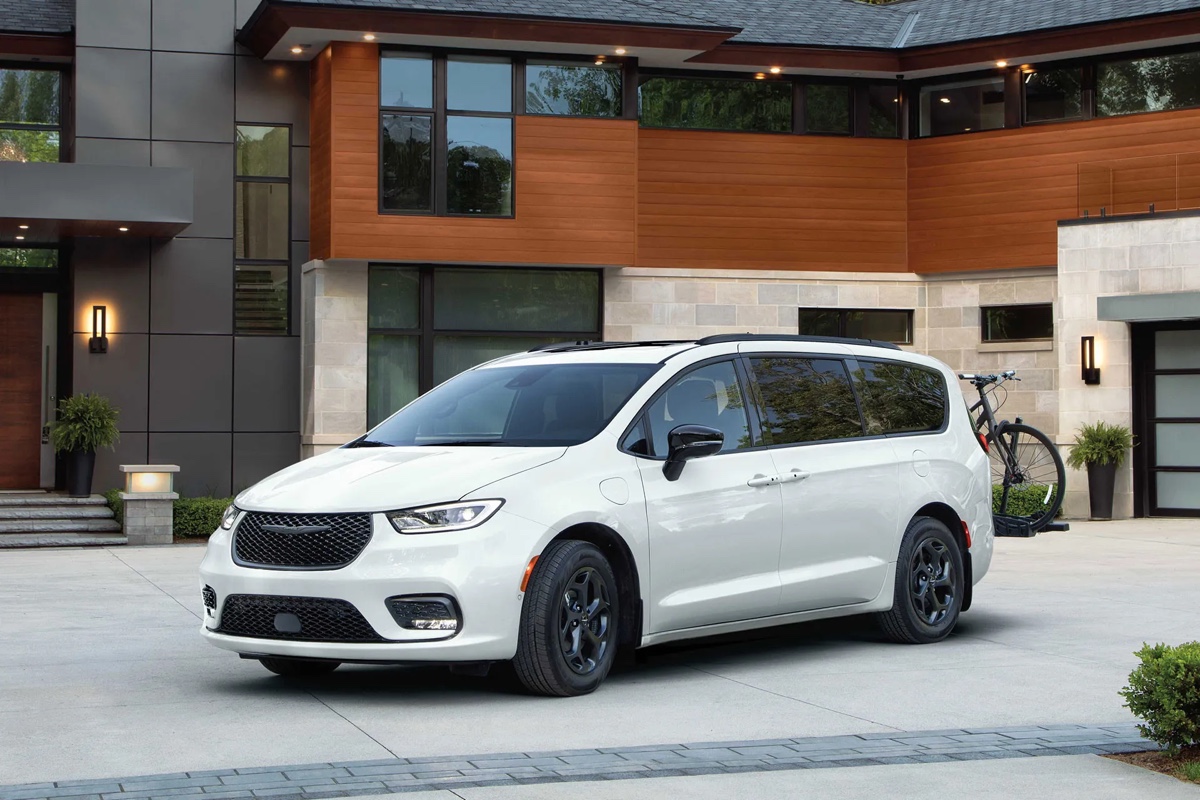 Chrysler Pacifica hybride 2026 blanche vue de trois quarts avant devant une résidence moderne, mettant en valeur le design, les proportions et l’élégance de la minifourgonnette hybride rechargeable.