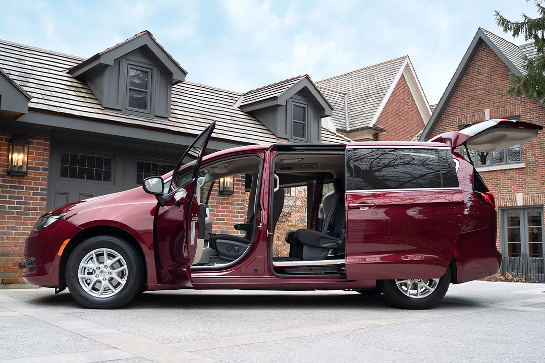 Vue latérale du Chrysler Grand Caravan 2024 avec portières ouvertes devant une maison