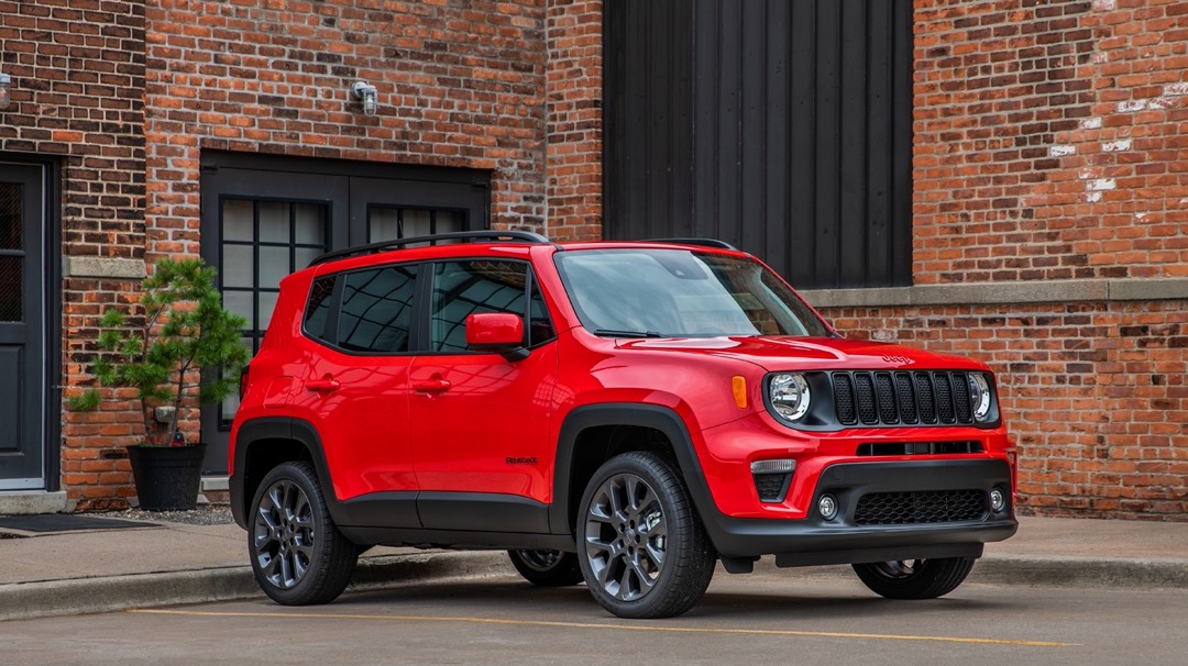Jeep Renegade 2023 édition RED rouge vu de trois quarts avant en milieu urbain, mettant en valeur le format compact, le design carré distinctif et le positionnement du VUS sous-compact pour la ville.