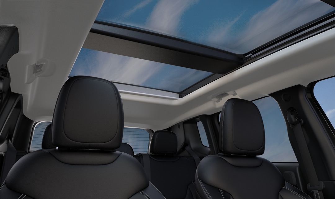 Habitacle du Jeep Renegade 2023 avec toit panoramique et sièges avant en cuir noir, mettant en valeur la luminosité intérieure, le confort et l’ergonomie du VUS sous-compact.