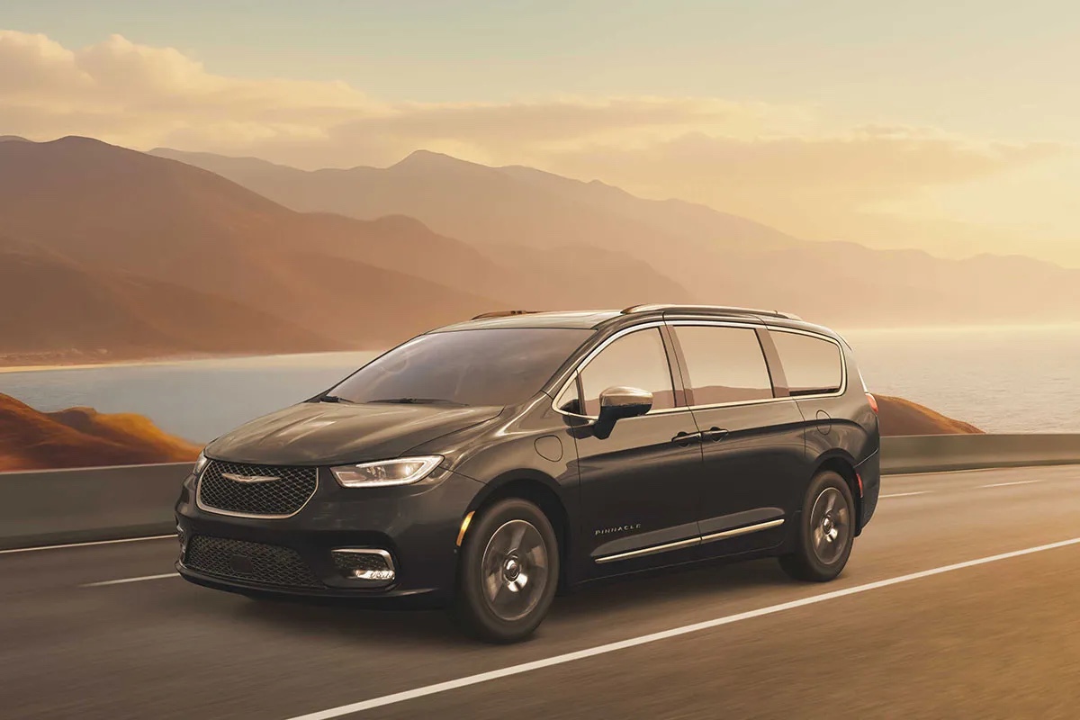 Chrysler Pacifica hybride 2026 noire en conduite sur route panoramique, illustrant le confort de roulement, l’autonomie et les performances de la minifourgonnette hybride rechargeable.