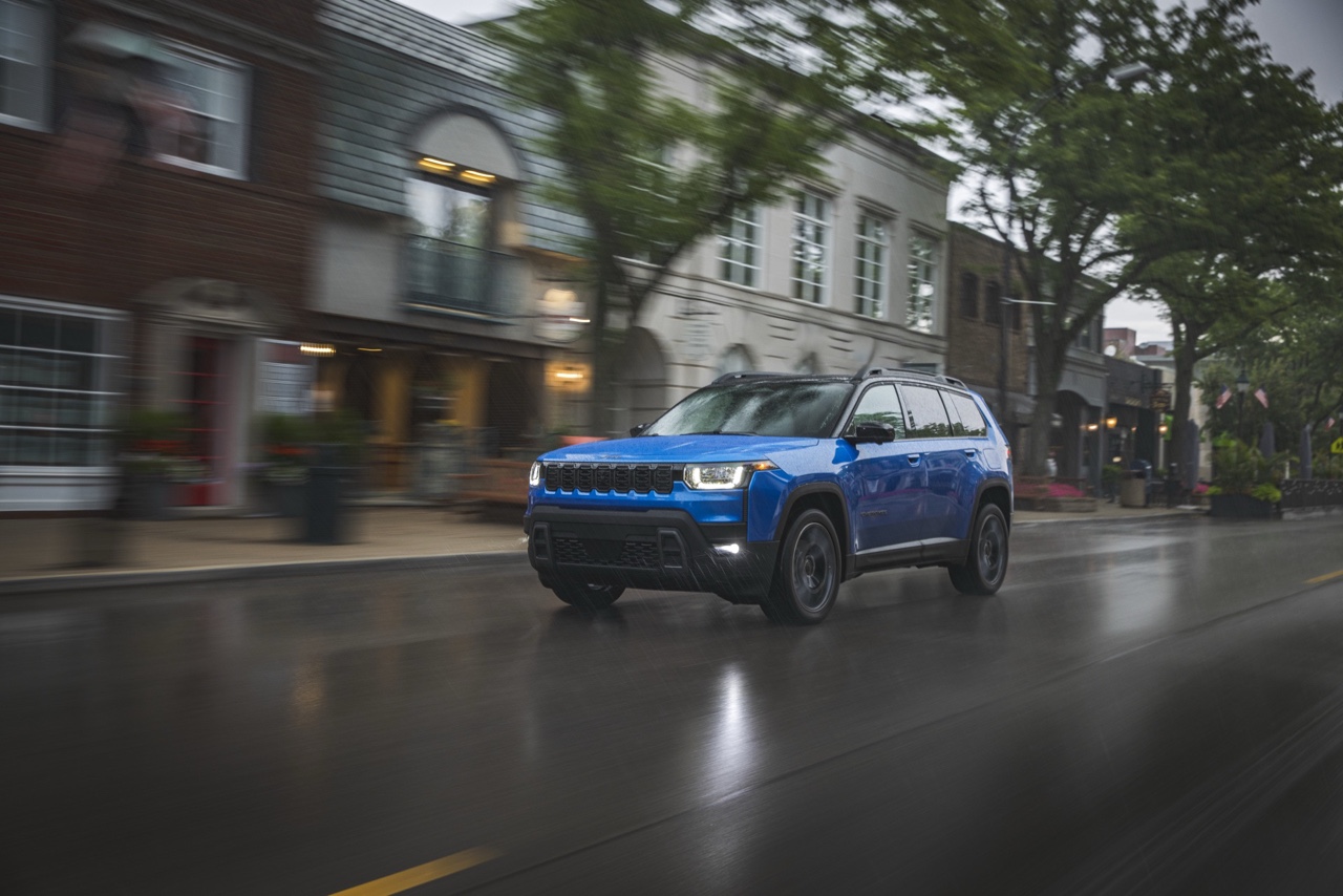 Jeep Cherokee hybride 2026 bleu roulant en milieu urbain sous la pluie, illustrant la tenue de route, la stabilité et le comportement du VUS en conditions réelles.