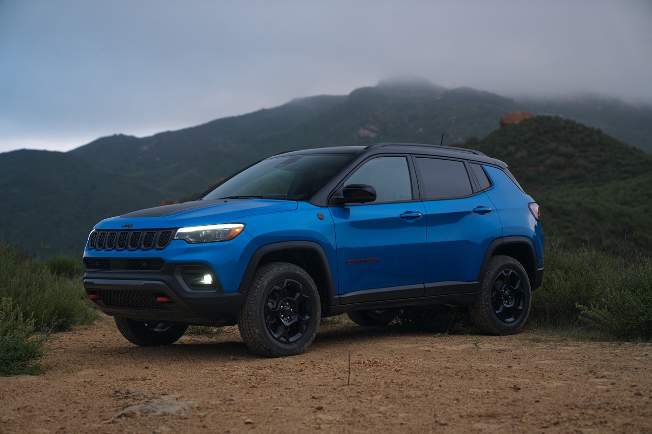Jeep Compass 2023 bleu vu de profil stationné en terrain montagneux, illustrant le gabarit plus spacieux, la garde au sol et le positionnement polyvalent du VUS compact.