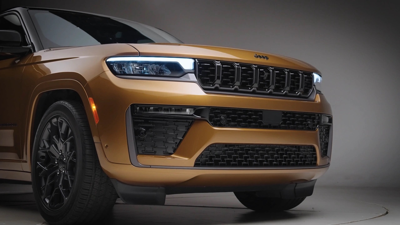 Gros plan de la calandre et du phare avant à DEL du Jeep Grand Cherokee 2026 doré, soulignant le design modernisé, la signature lumineuse et les détails de finition.