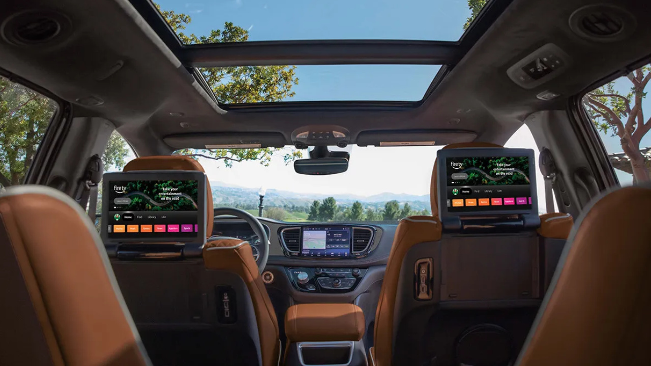 Habitacle de la Chrysler Grand Caravan 2026 avec écrans arrière, toit ouvrant et système multimédia, illustrant le confort et les technologies pour les passagers.