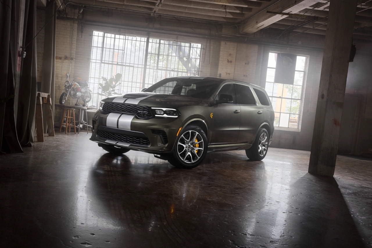 Dodge Durango 2026 vert kaki vu de trois quarts avant à l’intérieur d’un bâtiment industriel, mettant en valeur la calandre sportive et les bandes contrastantes.
